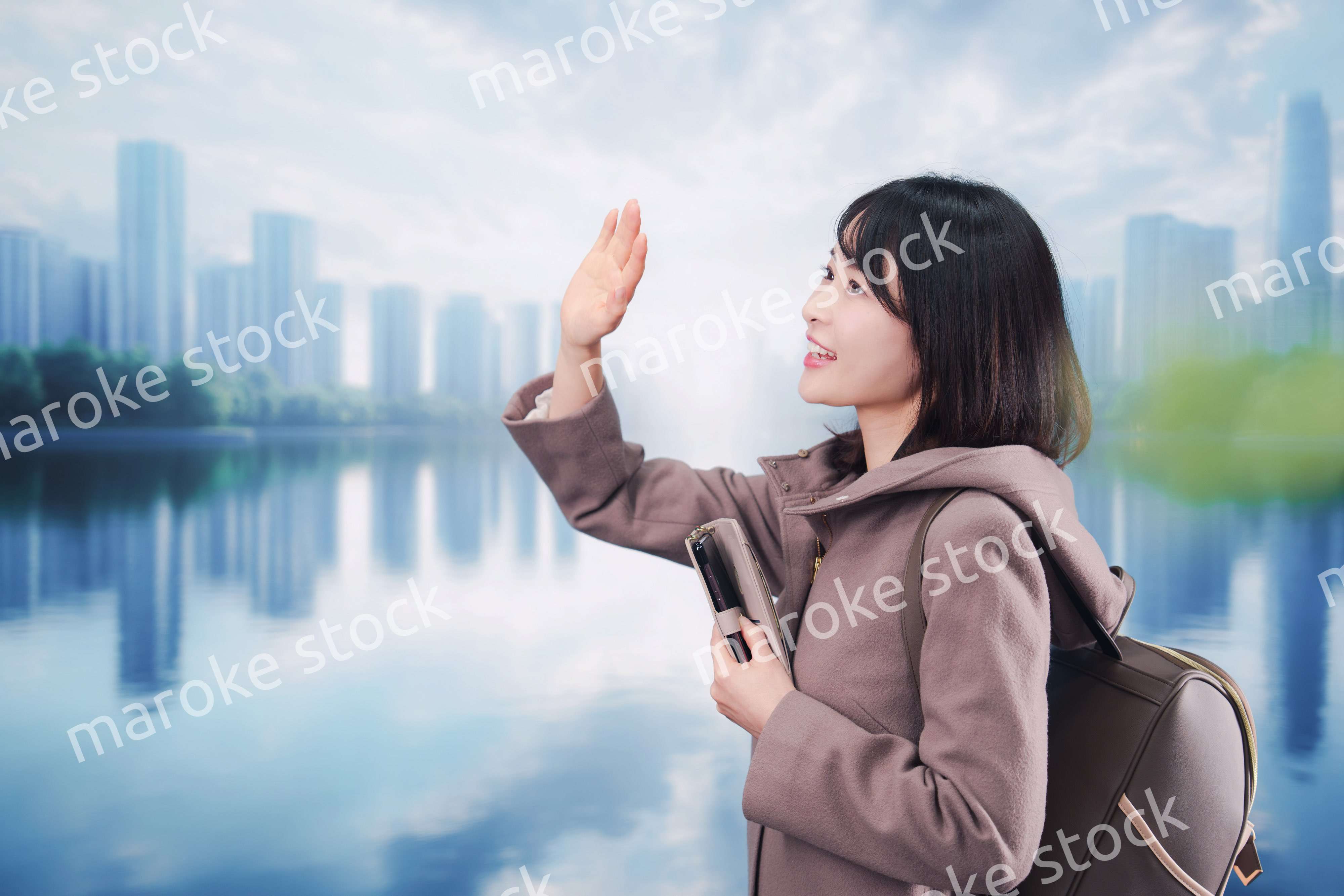 コートを着てスマホを使いながら外を歩く若い女性