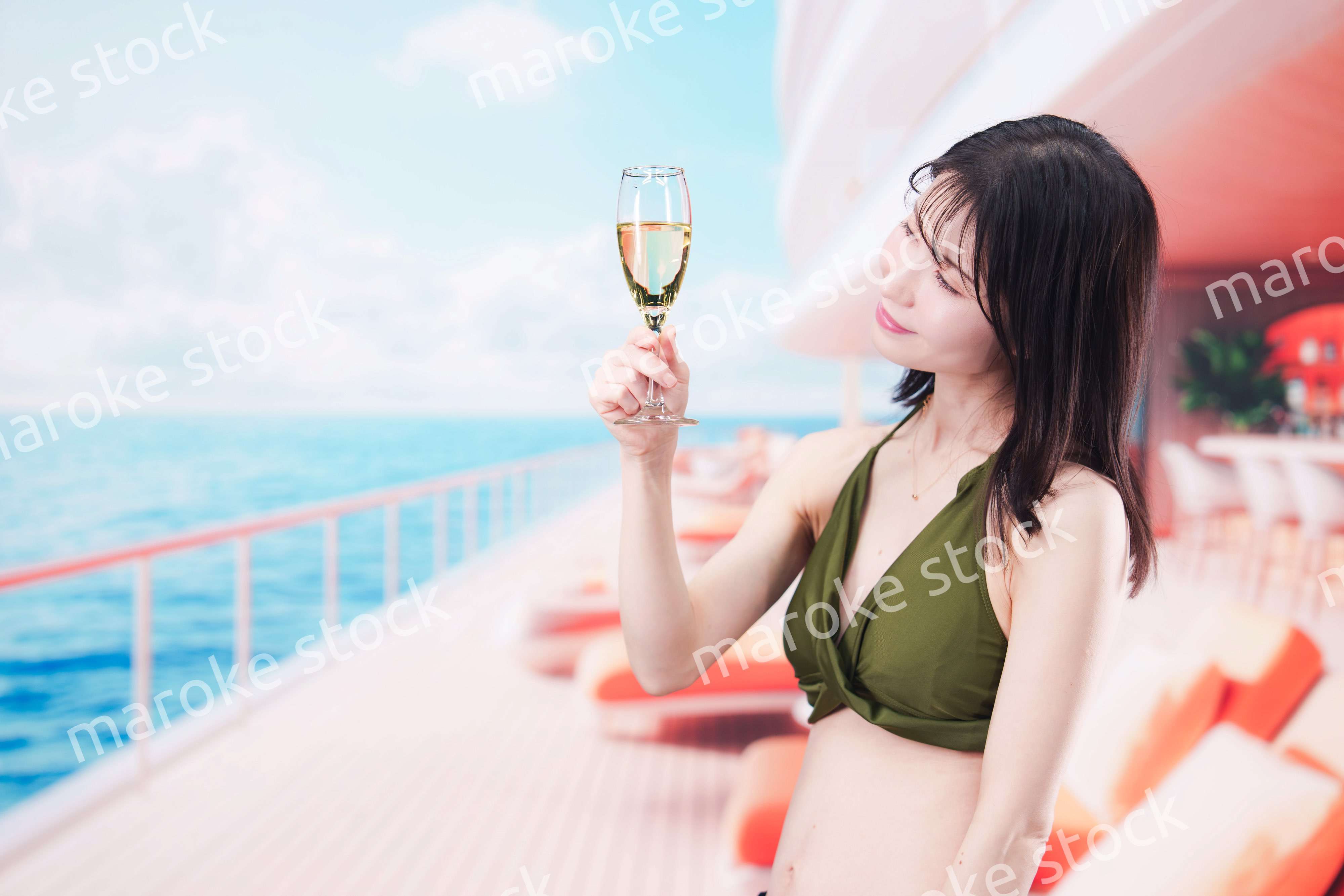 クルーズ船で水着を着てスパークリングワインを飲む若い女性