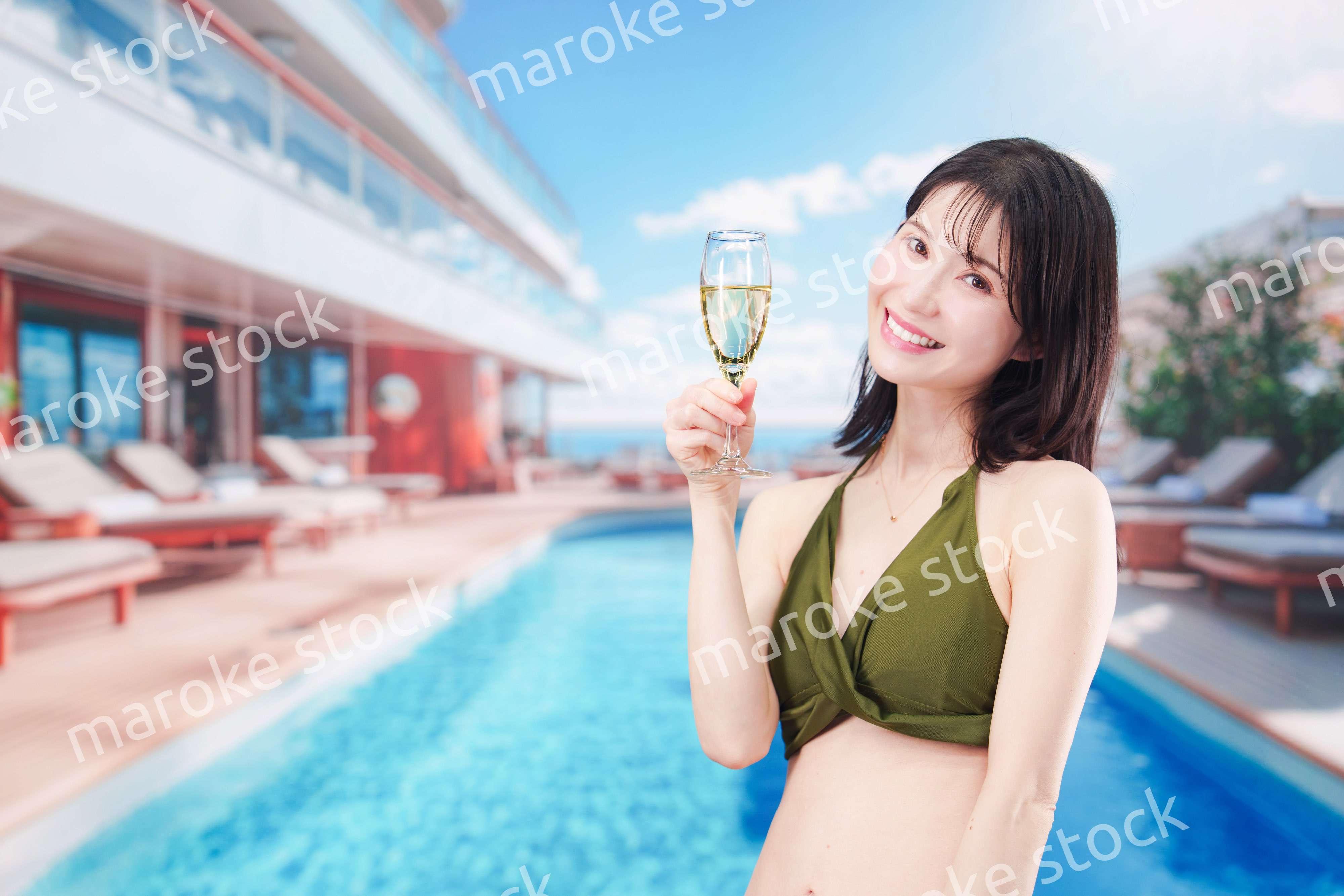 リゾートのプールで水着を着てスパークリングワインを飲む若い女性