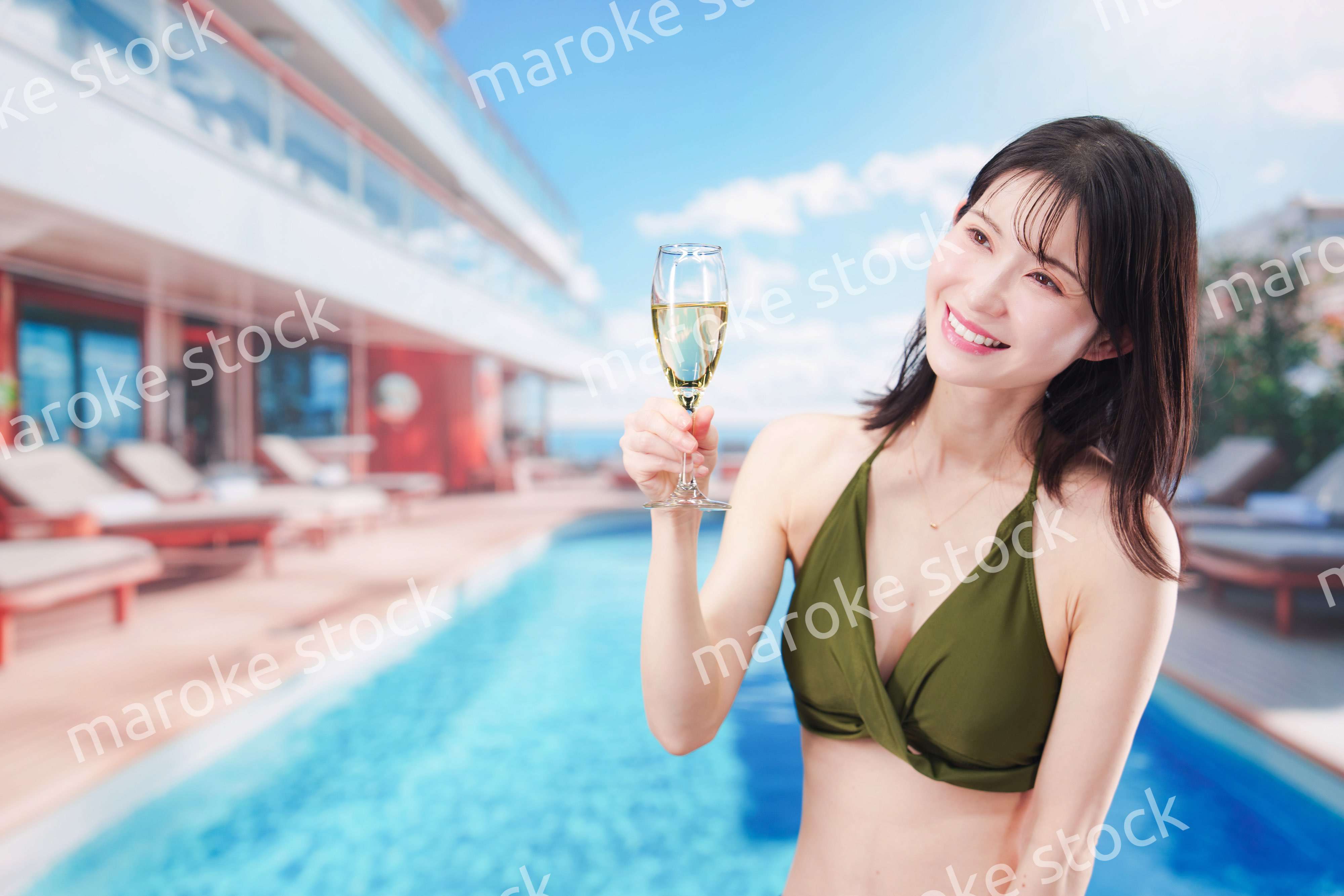 リゾートのプールで水着を着てスパークリングワインを飲む若い女性