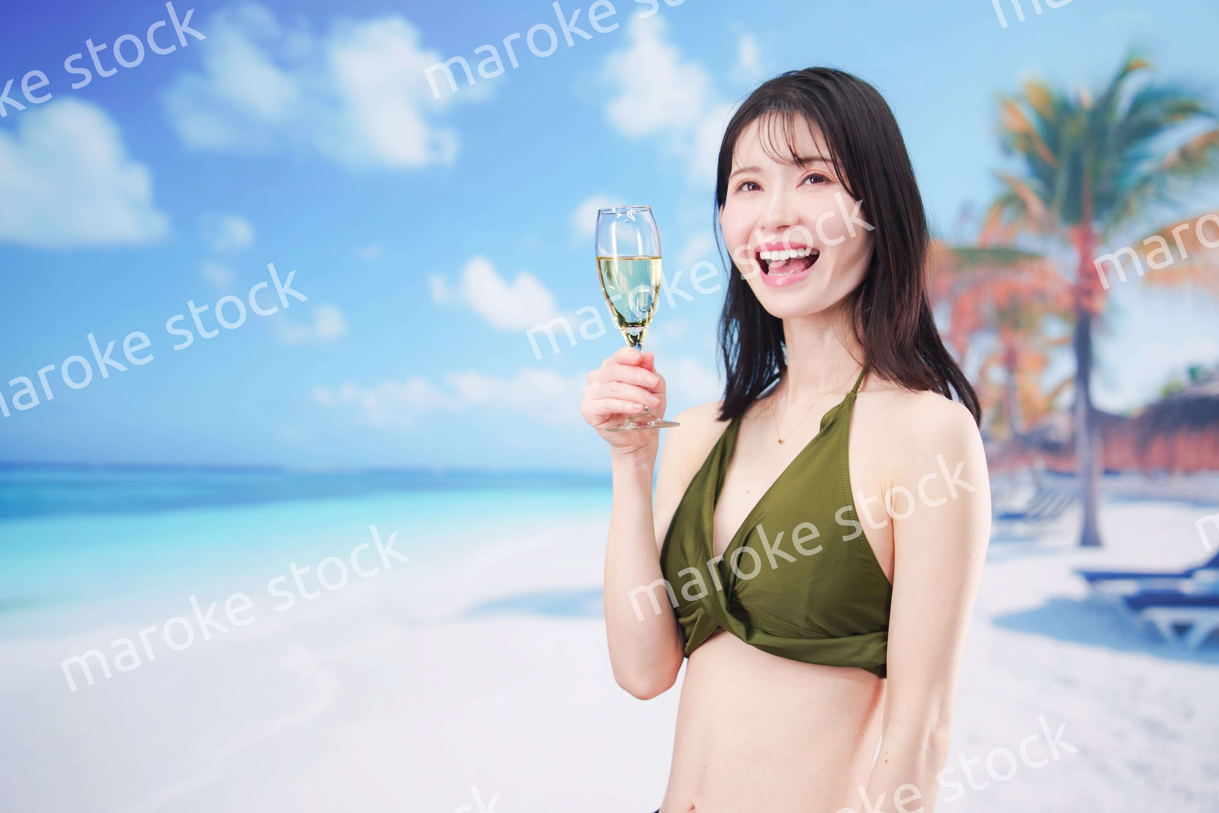 真夏のビーチでスパークリングワインを飲む水着を着た若い女性