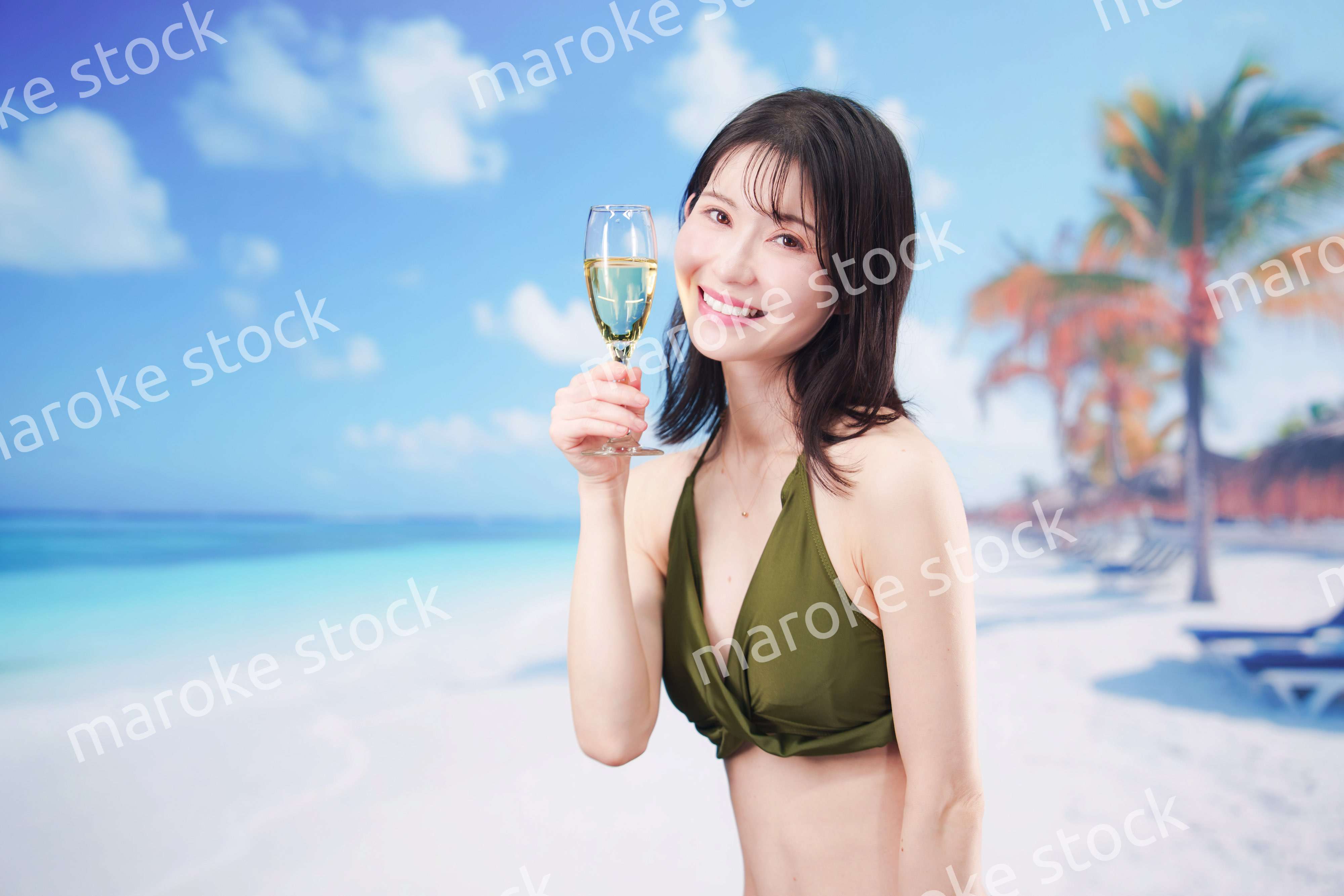 真夏のビーチでスパークリングワインを飲む水着を着た若い女性