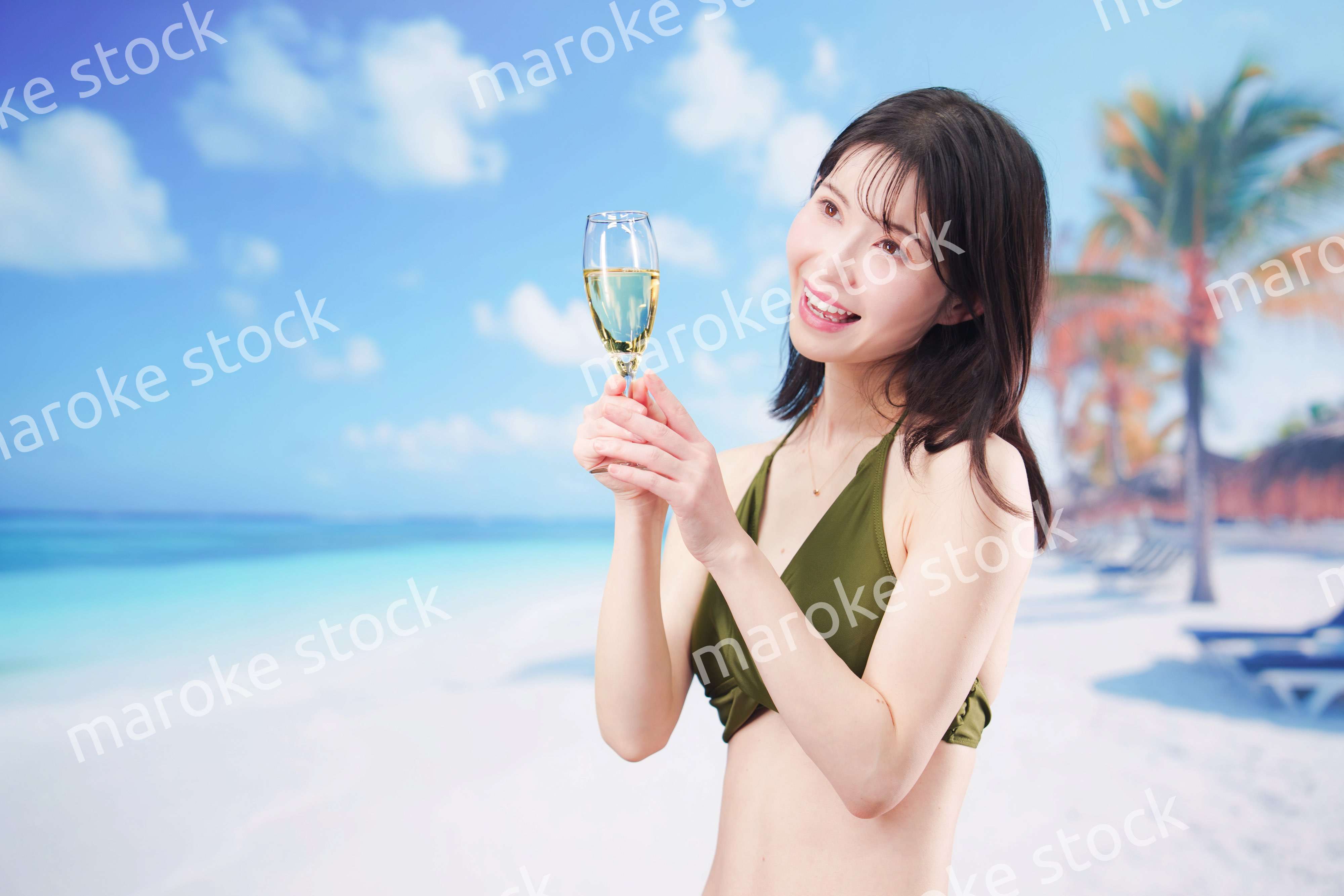 真夏のビーチでスパークリングワインを飲む水着を着た若い女性