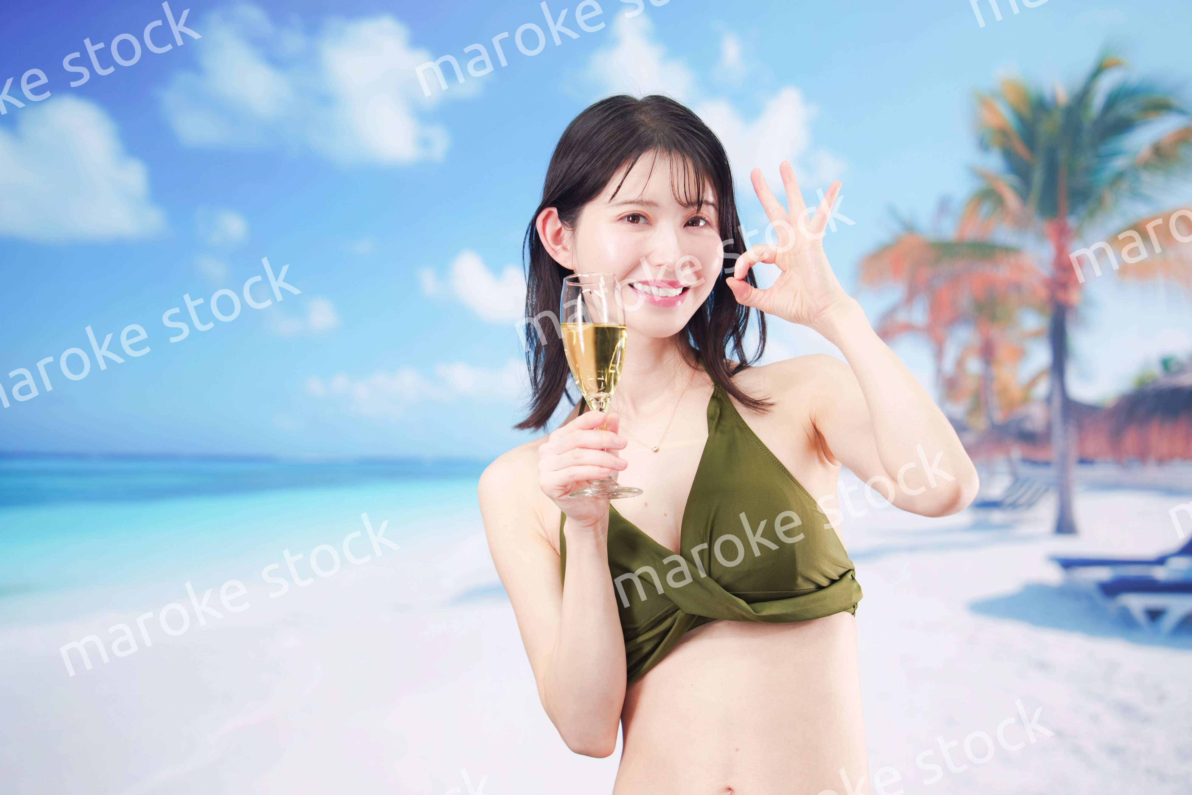 真夏のビーチでスパークリングワインを飲む水着を着た若い女性