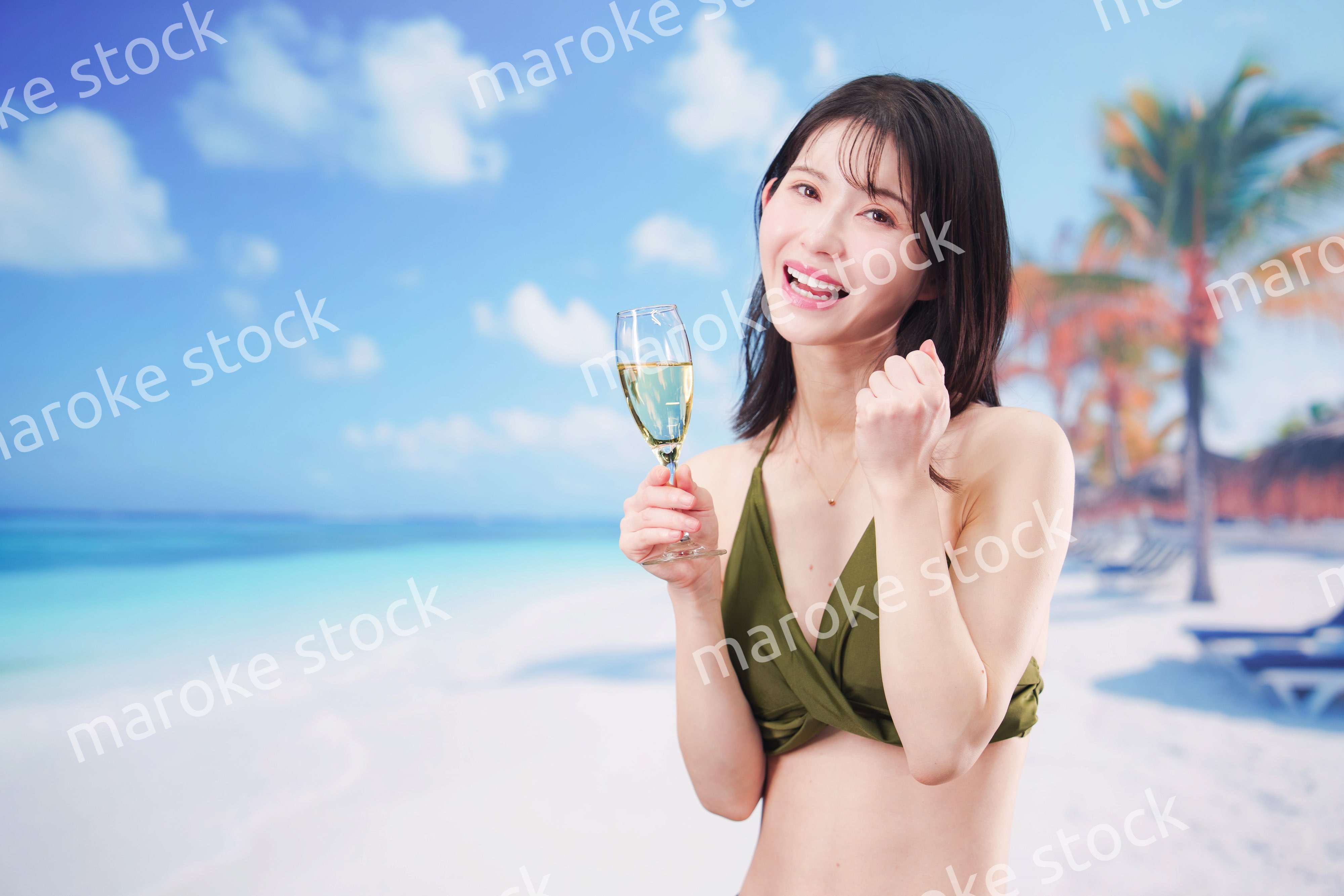 真夏のビーチでスパークリングワインを飲む水着を着た若い女性