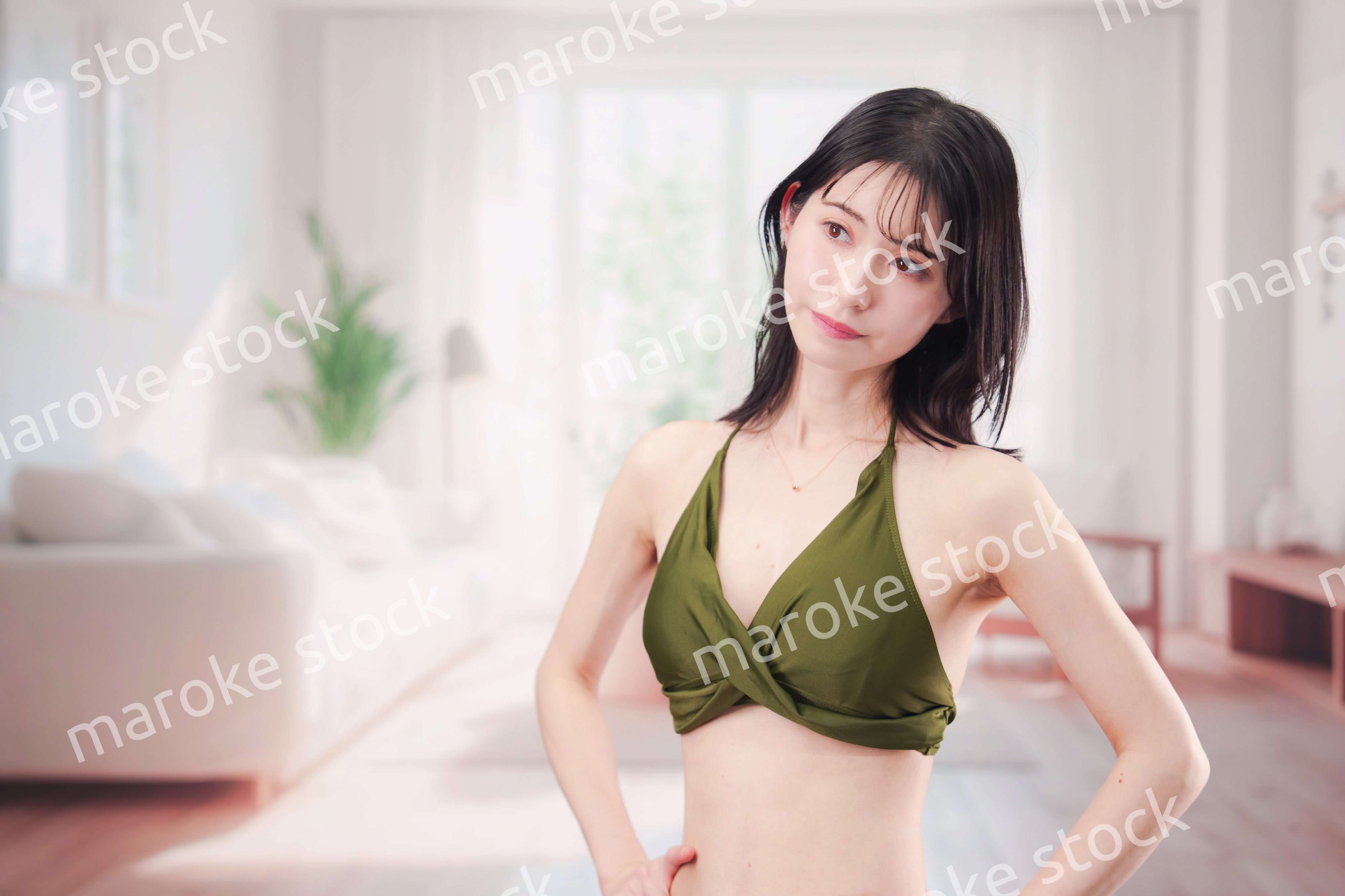 家で水着を試着して体型を気にする若い女性