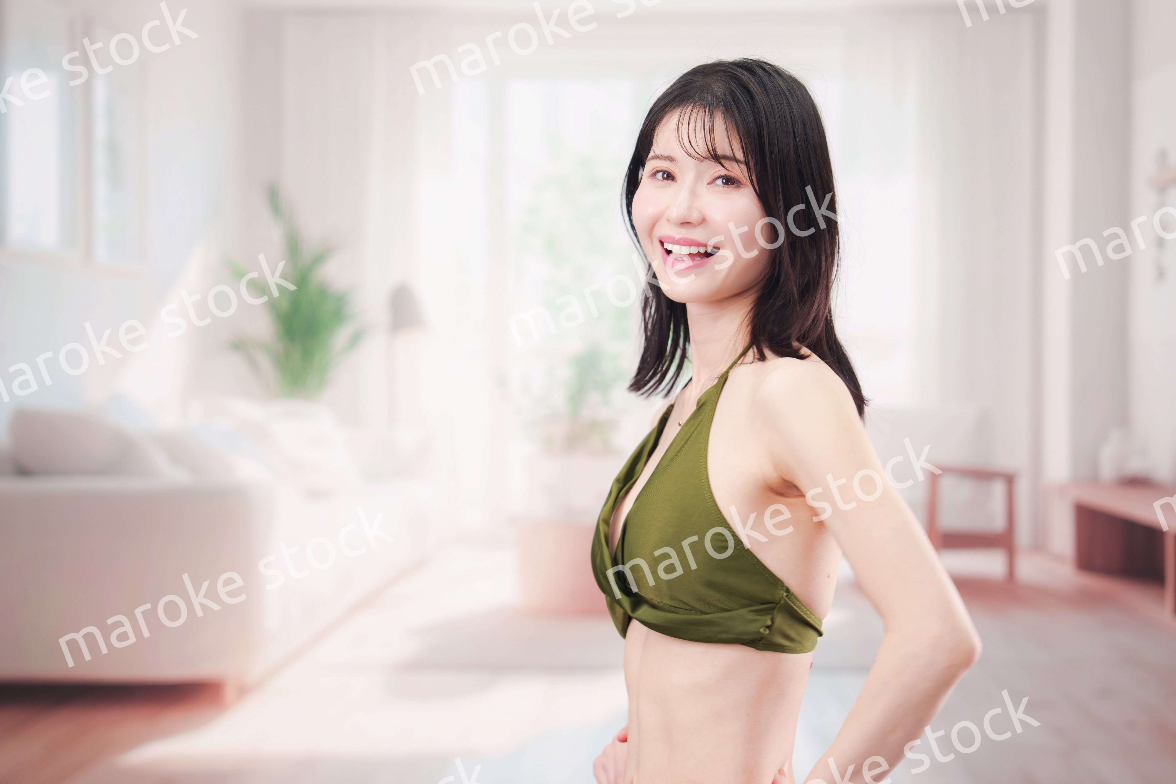 家で水着を試着して体型を気にする若い女性