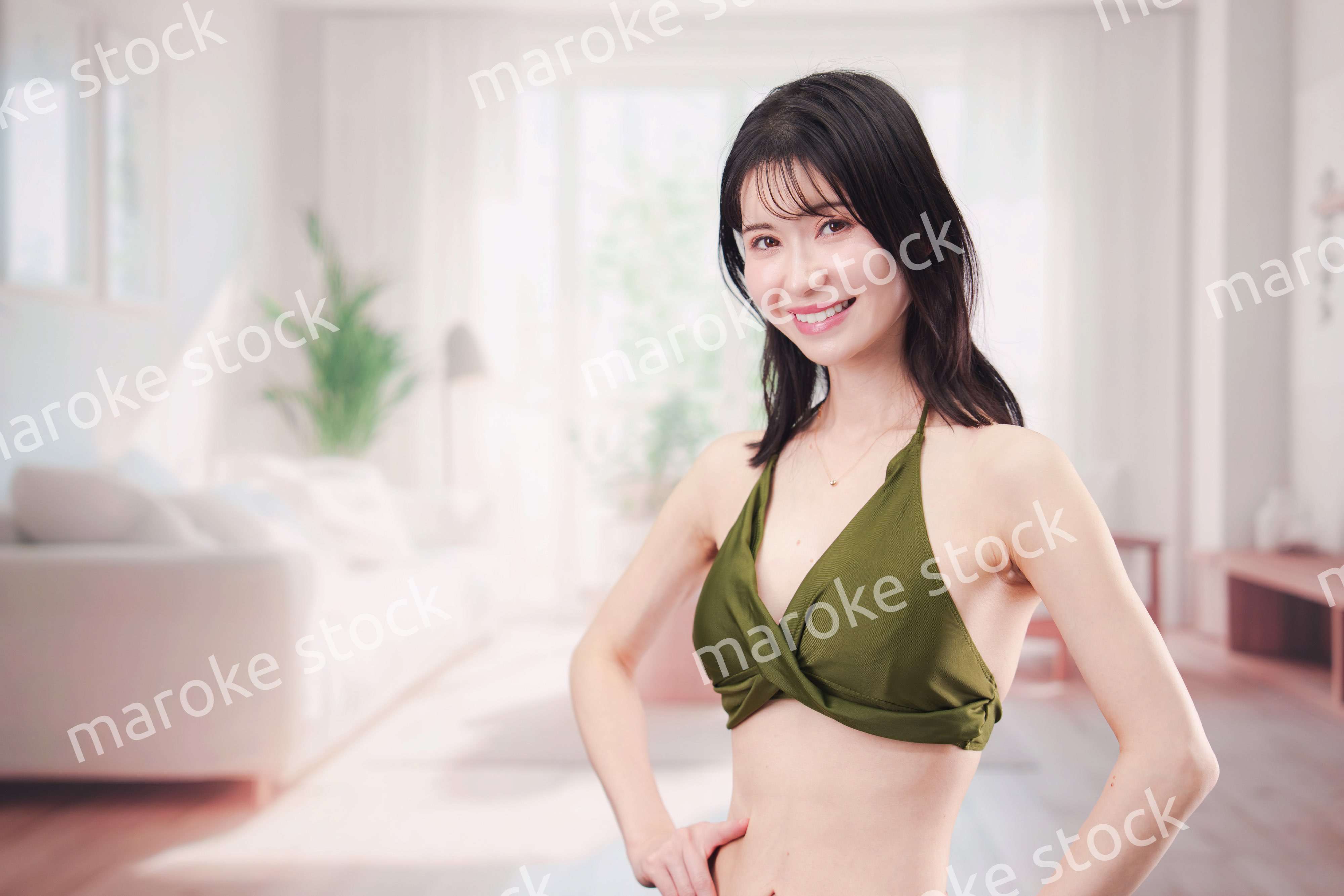 家で水着を試着して体型を気にする若い女性