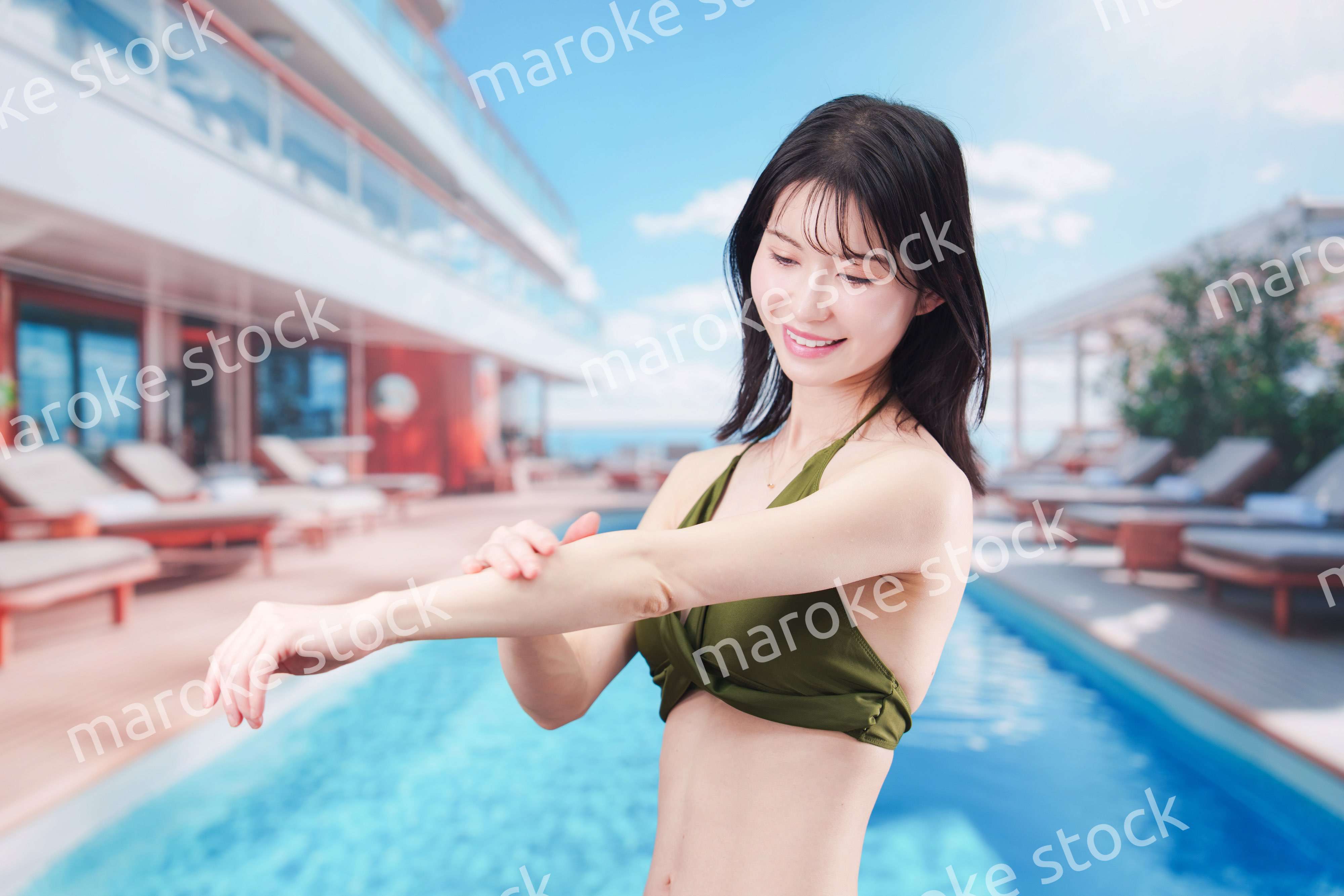 真夏のリゾートで日焼け止めクリームを塗る若い女性