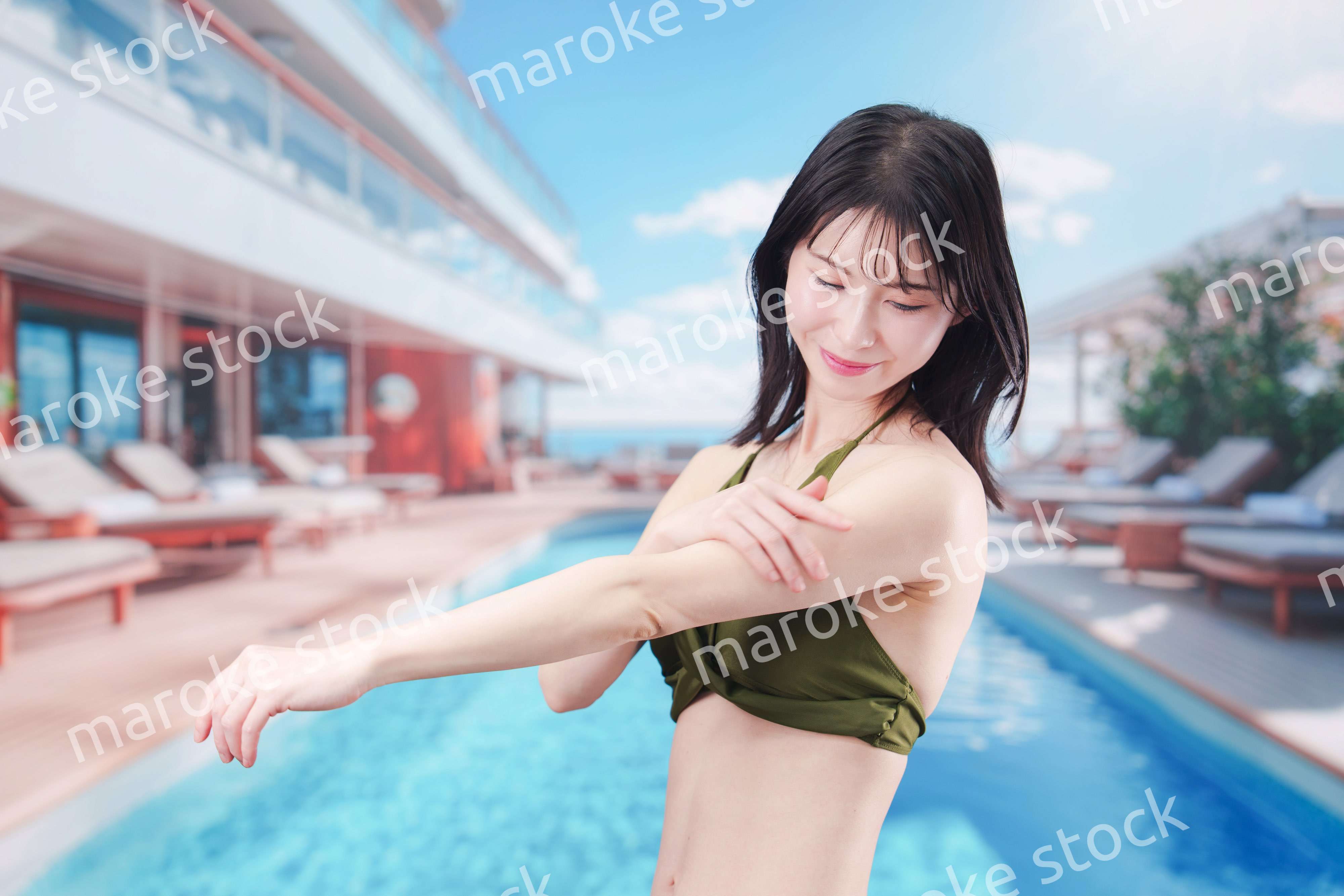 真夏のリゾートで日焼け止めクリームを塗る若い女性