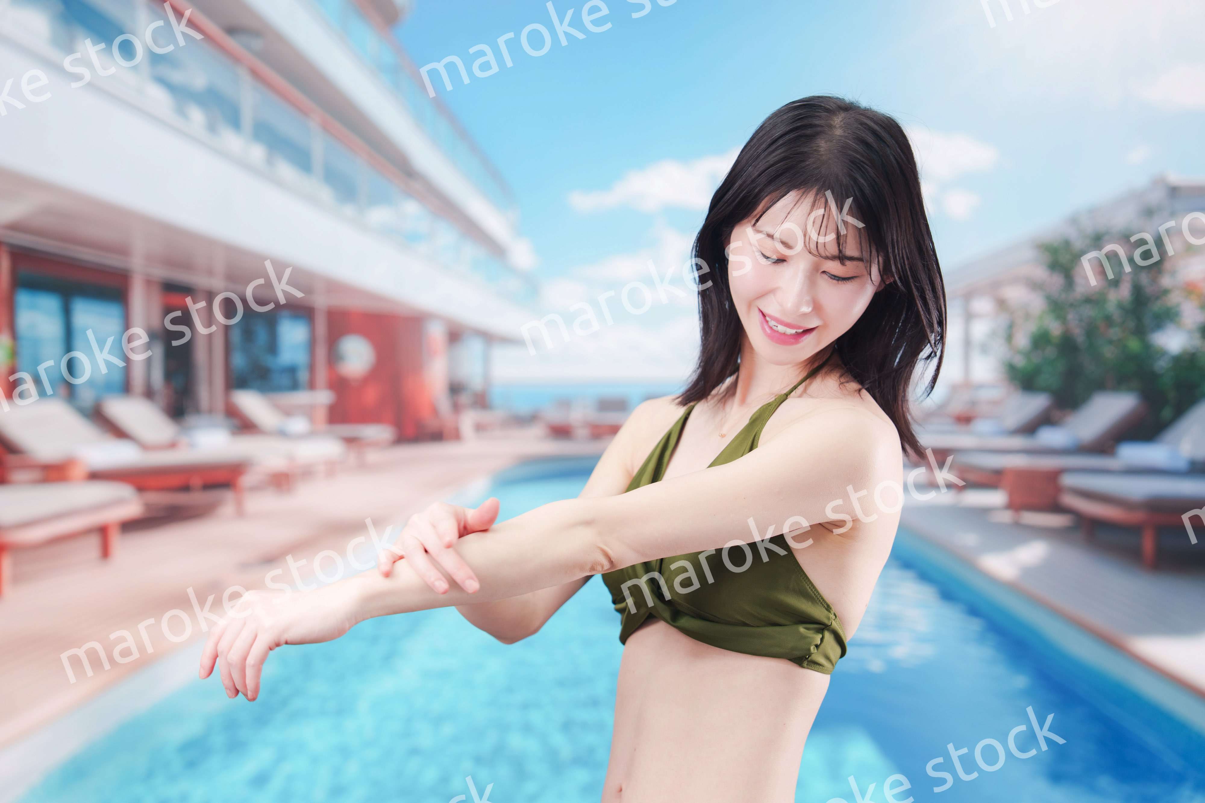 真夏のリゾートで日焼け止めクリームを塗る若い女性