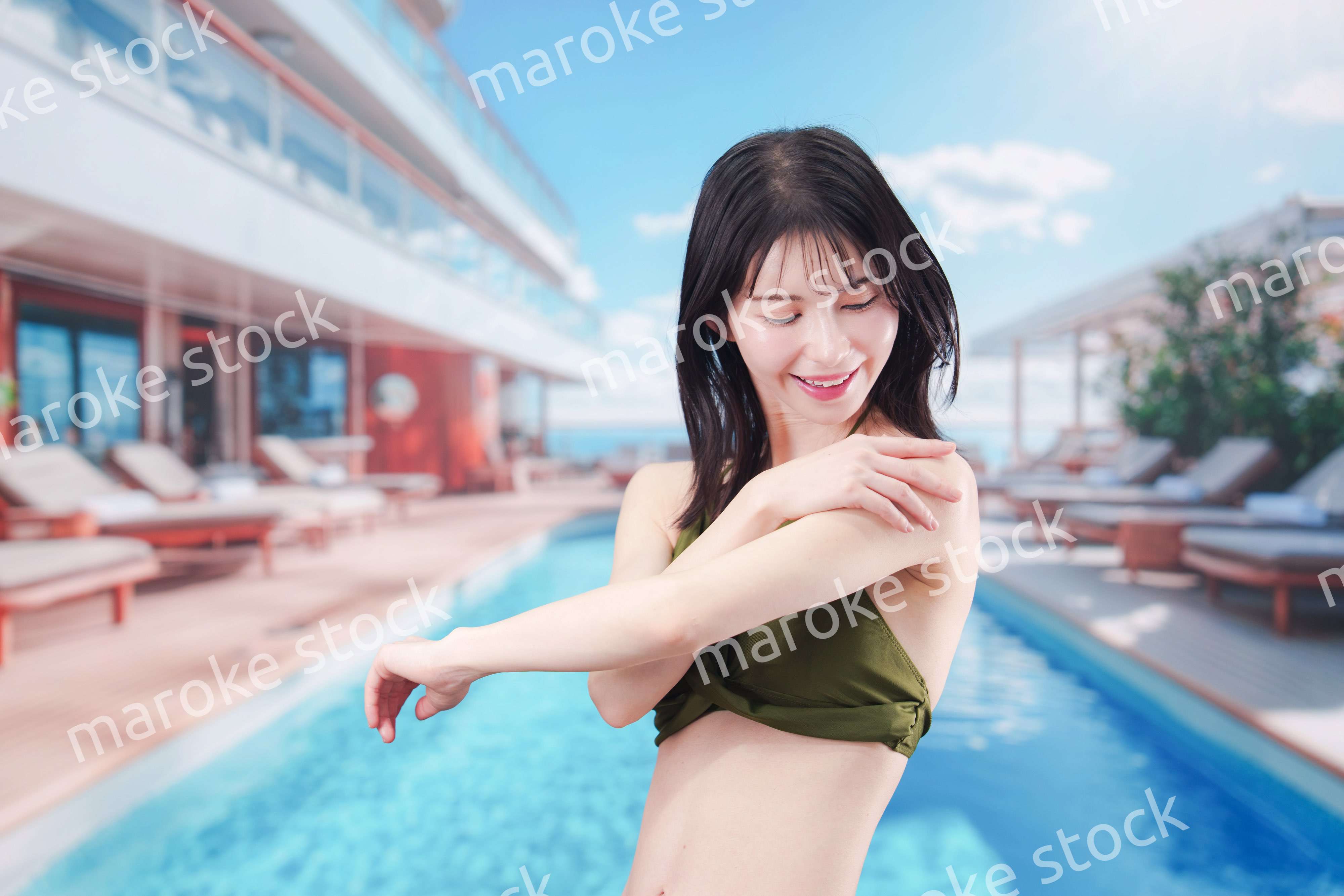 真夏のリゾートで日焼け止めクリームを塗る若い女性