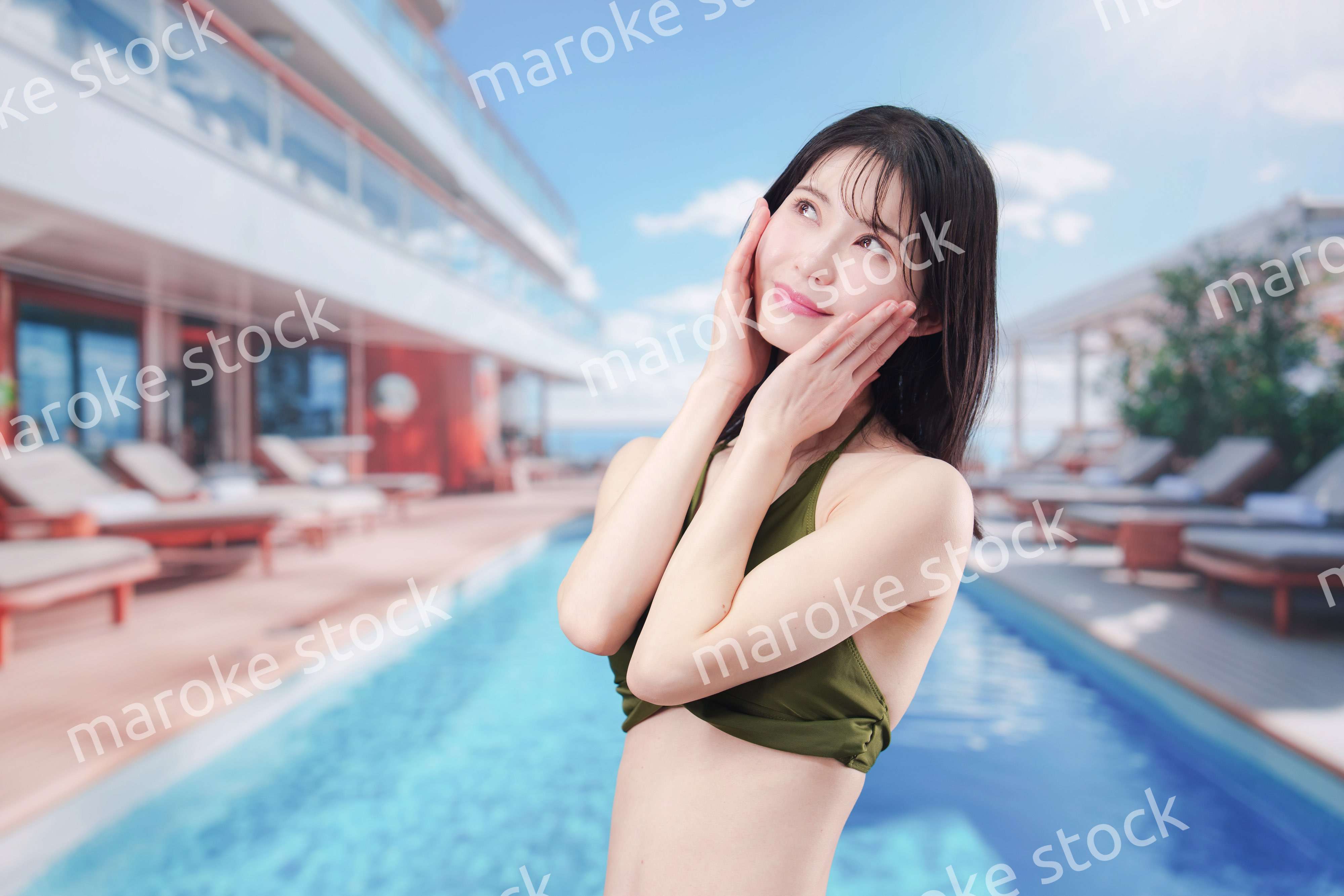 太陽が降り注ぐリゾートで顔に日焼け止めを塗る水着姿の女性