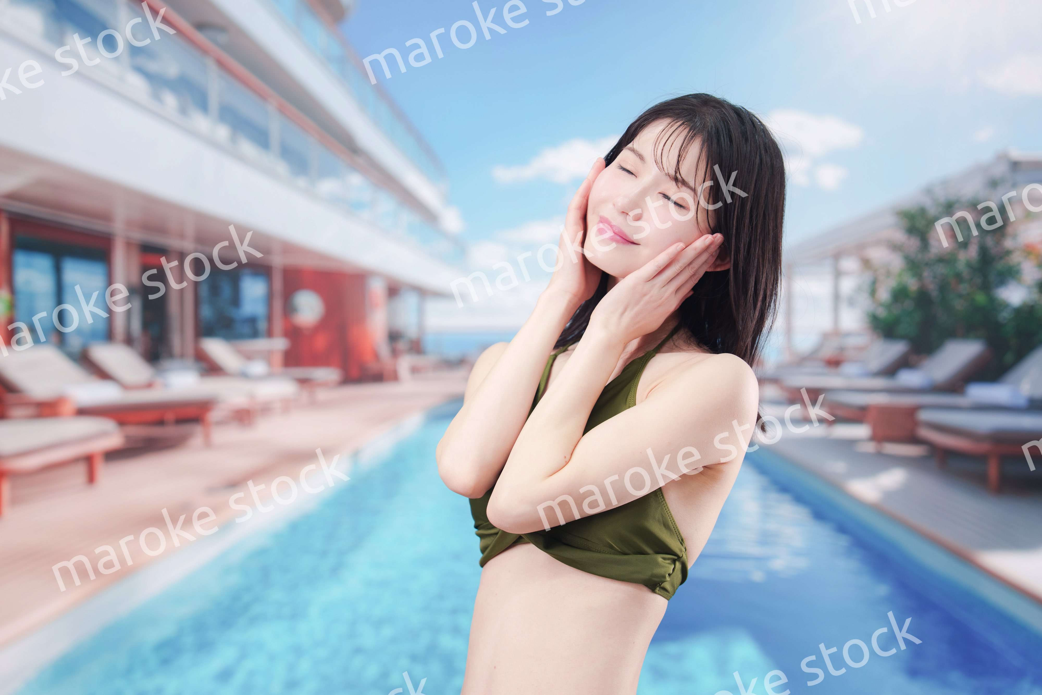 太陽が降り注ぐリゾートで顔に日焼け止めを塗る水着姿の女性