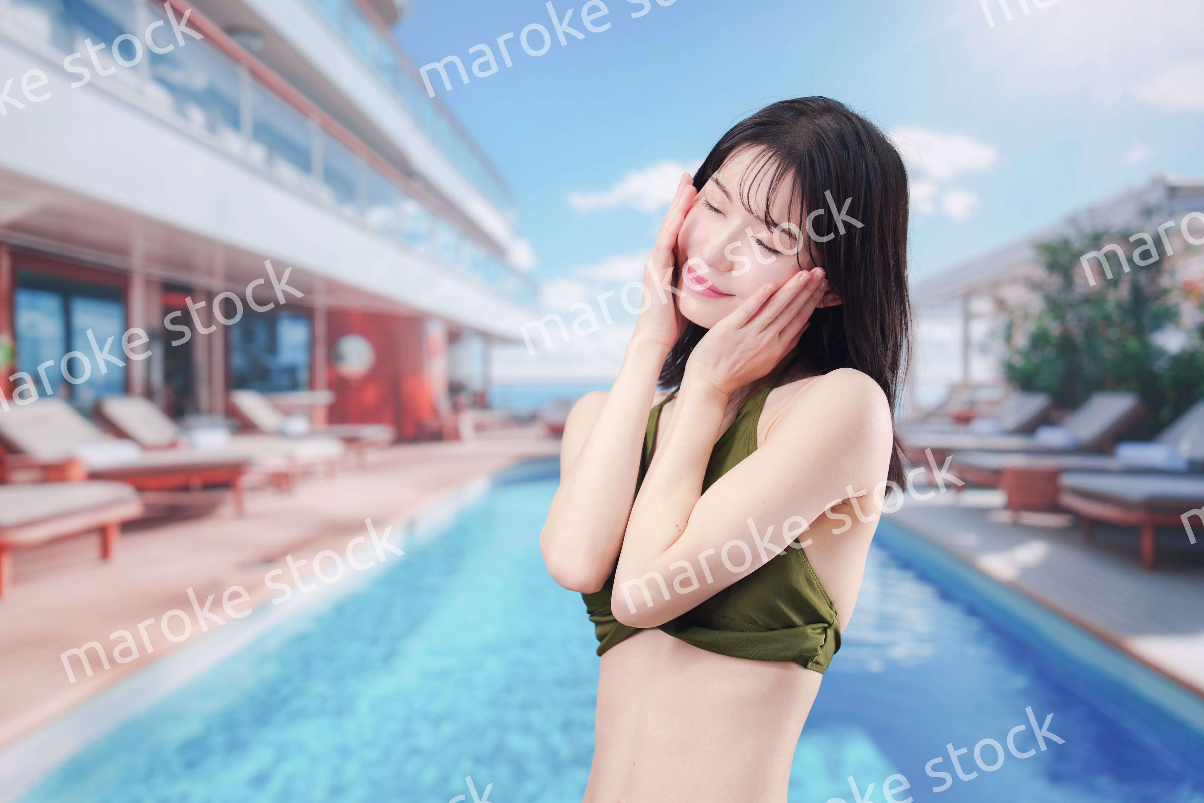 太陽が降り注ぐリゾートで顔に日焼け止めを塗る水着姿の女性