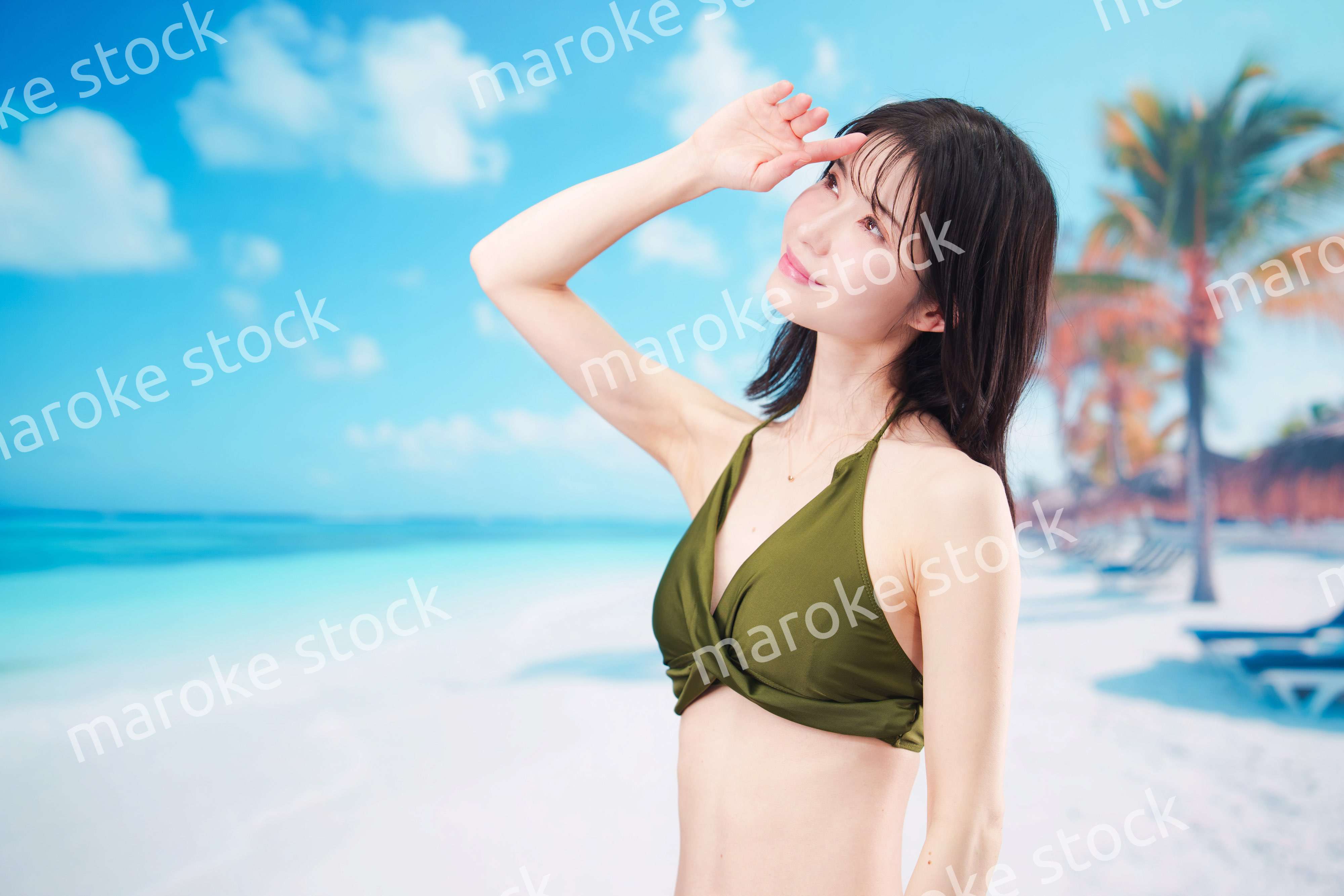 青空のビーチで水着を着た若い女性