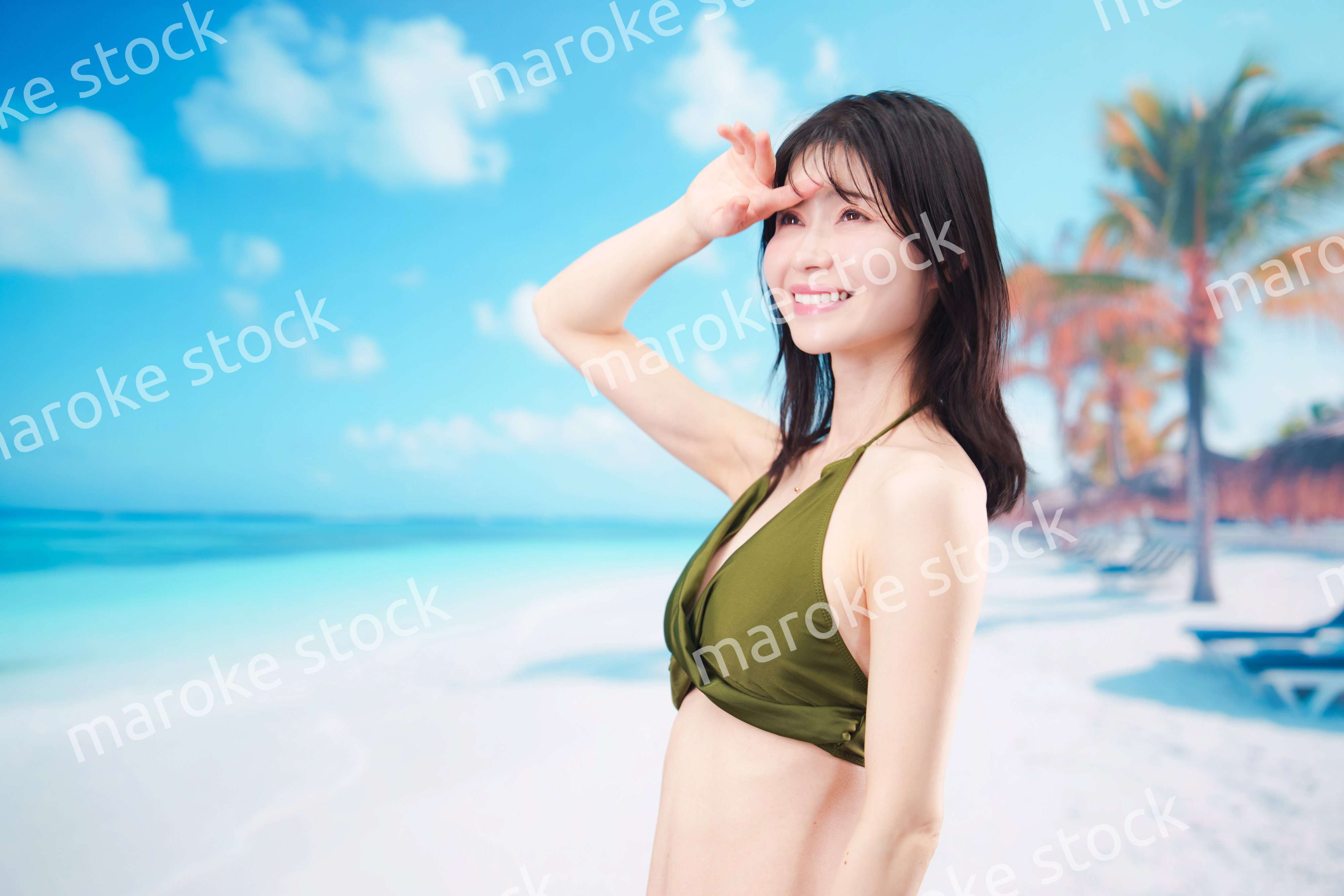 青空のビーチで水着を着た若い女性