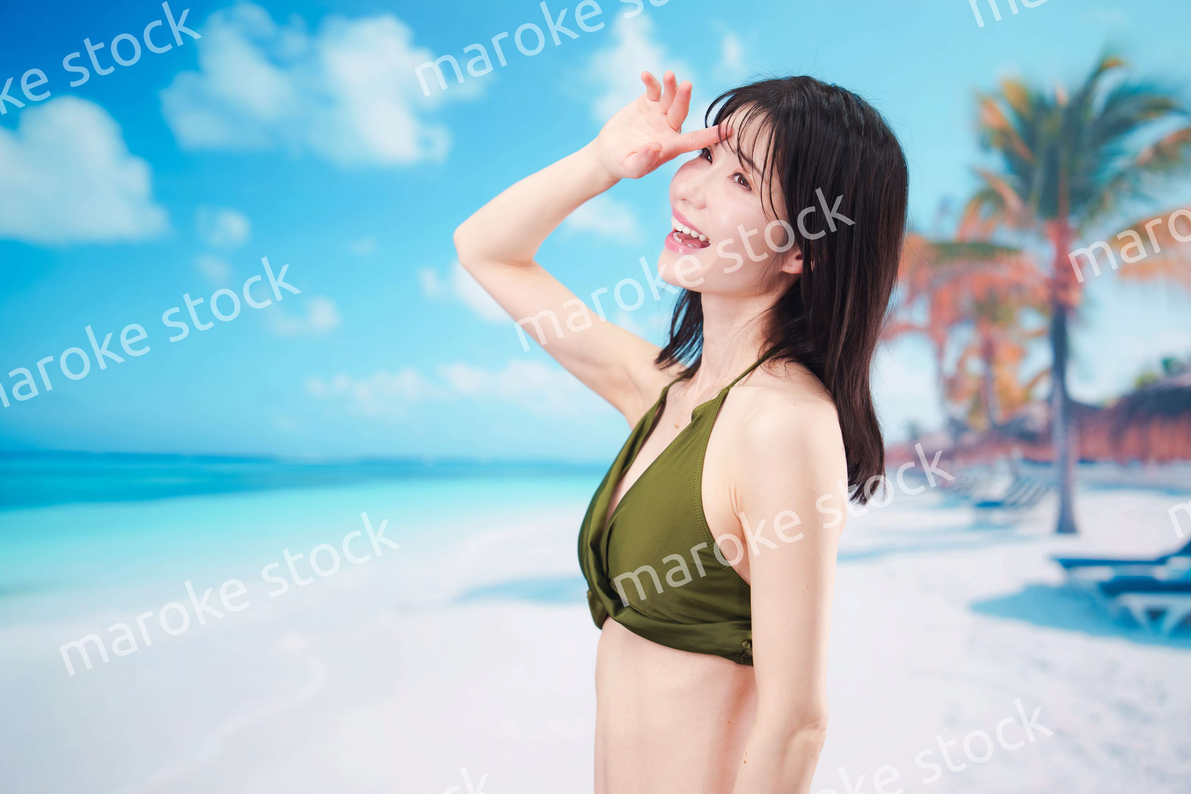 青空のビーチで水着を着た若い女性