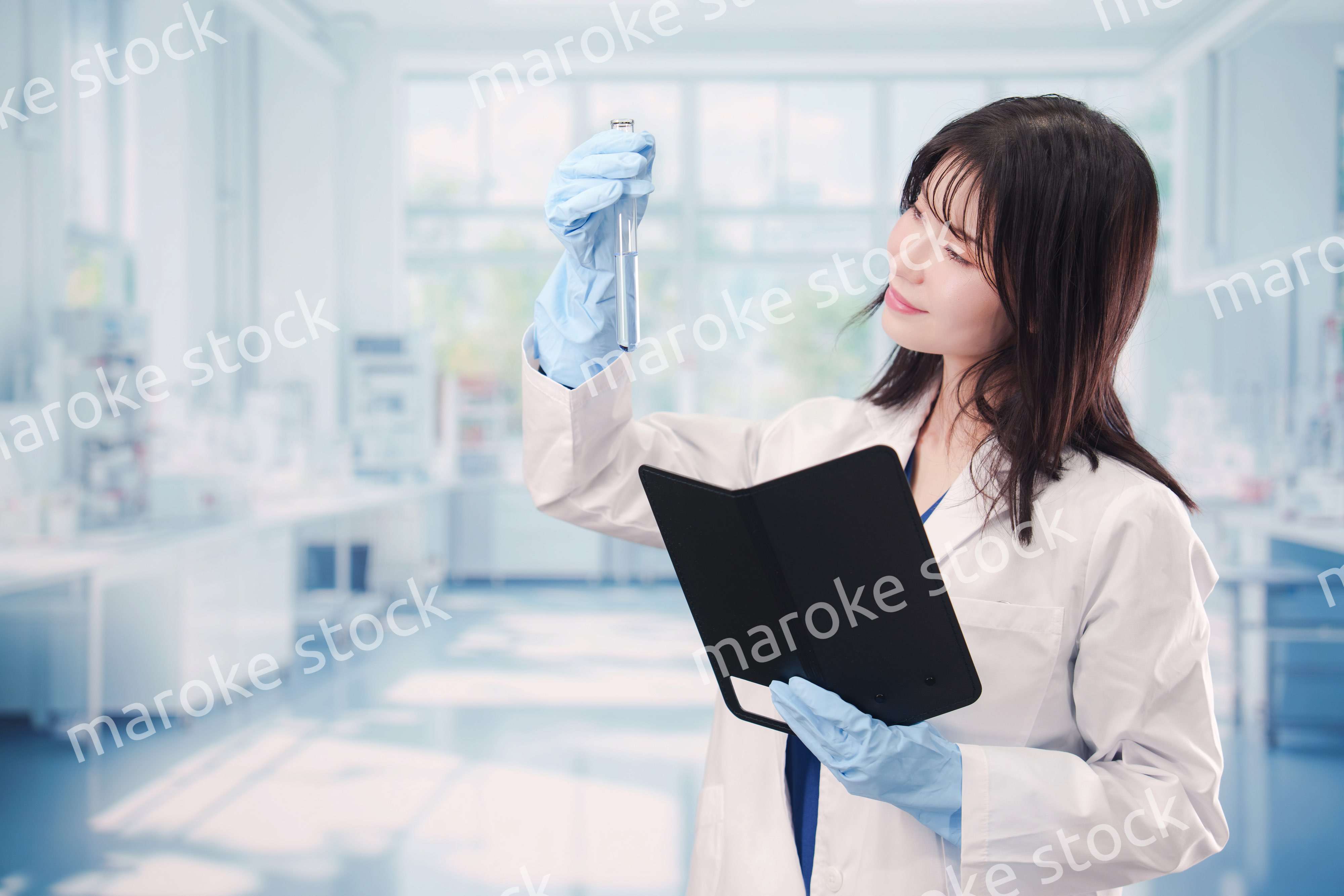 実験室で試験管の薬品を扱う若い女性