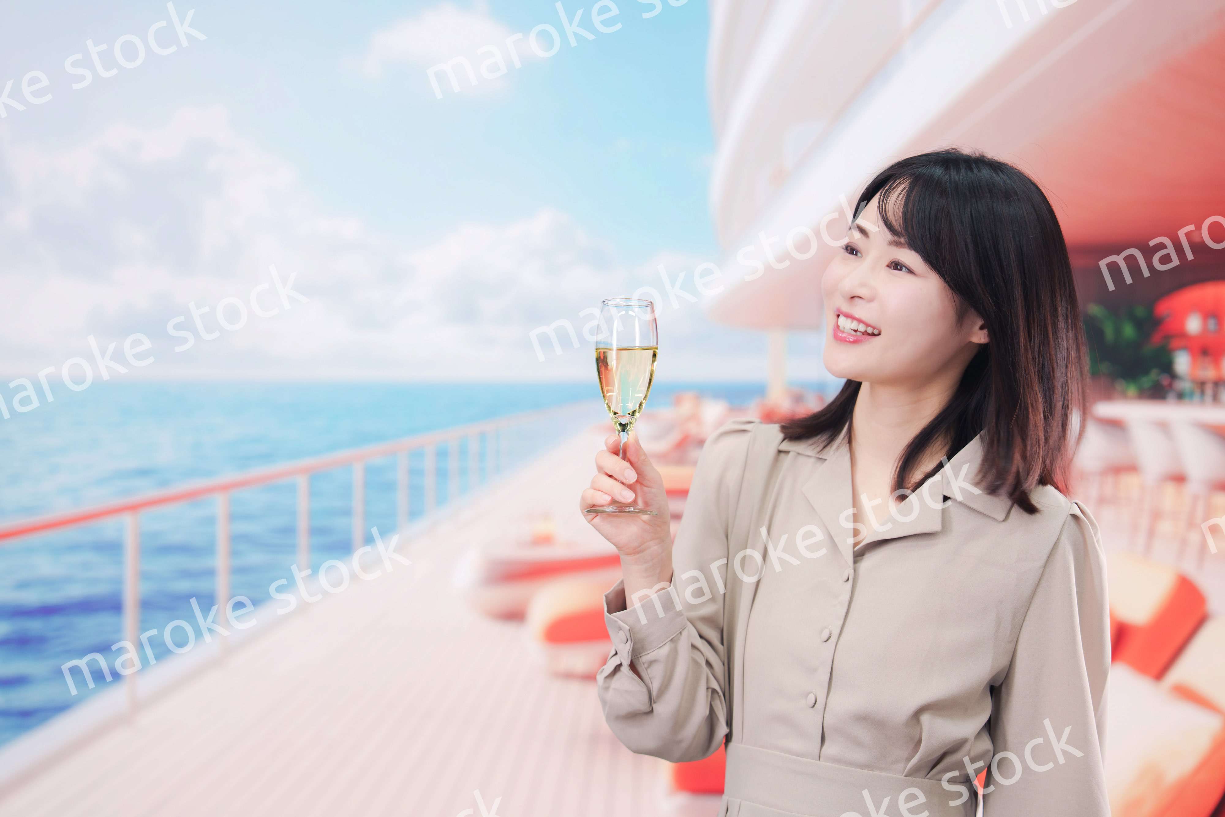 クルーズ船のデッキでスパークリングワインを飲む若い女性