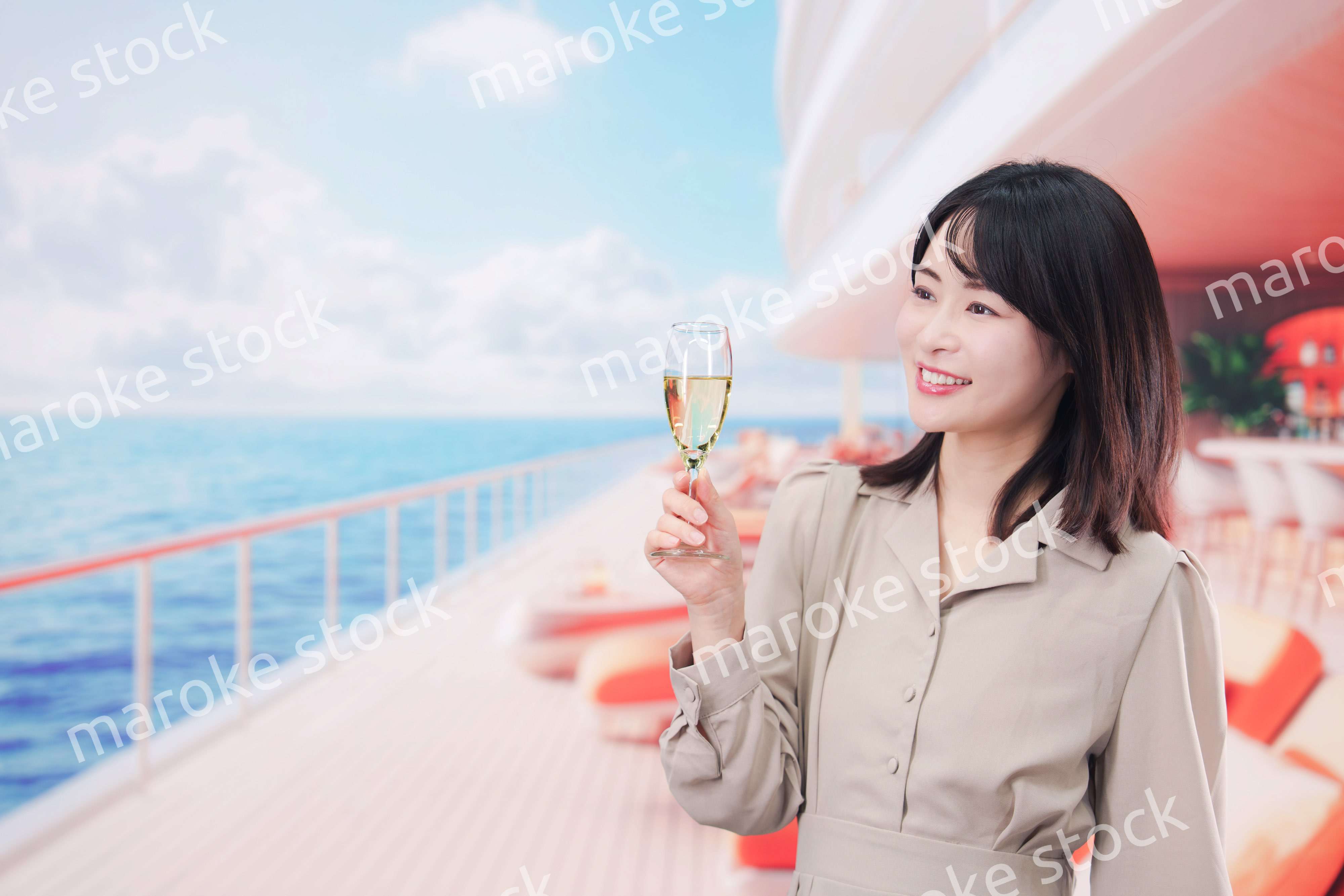 クルーズ船のデッキでスパークリングワインを飲む若い女性