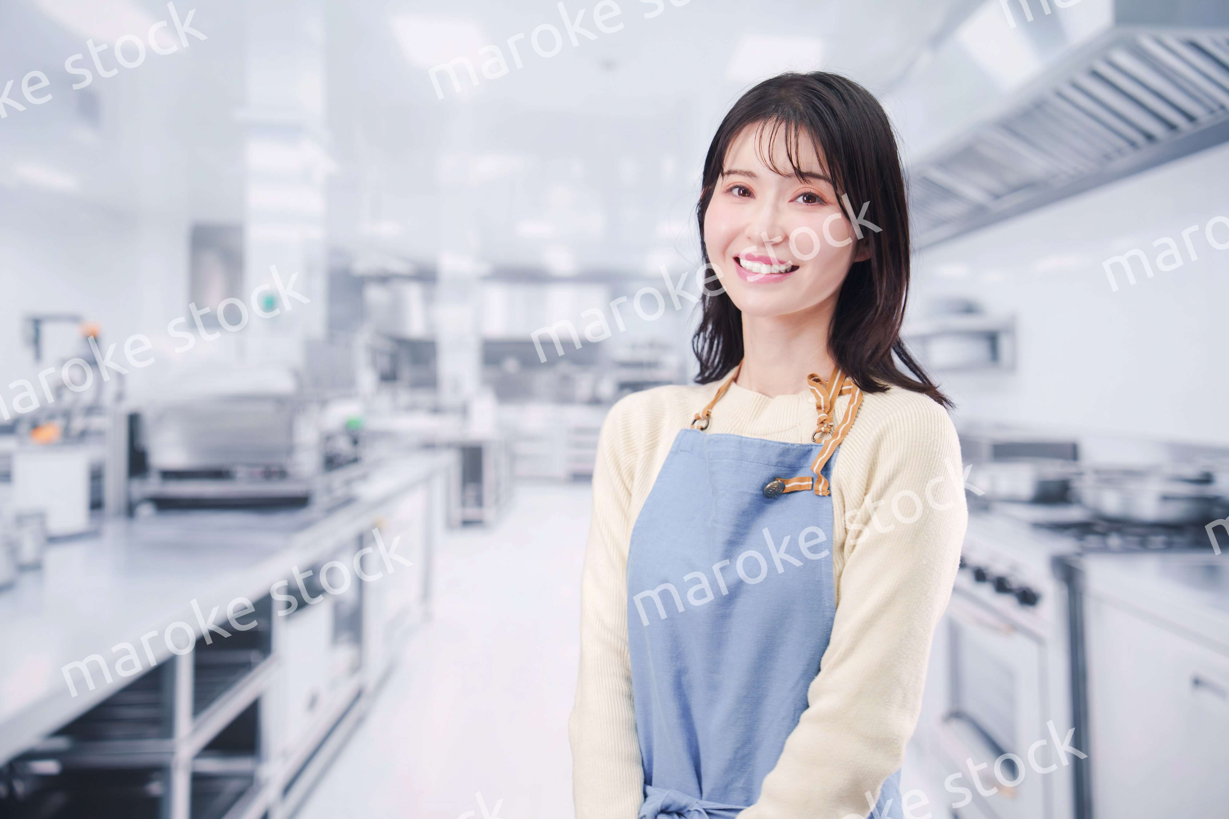 大きな厨房でエプロンを着る若い女性シェフ