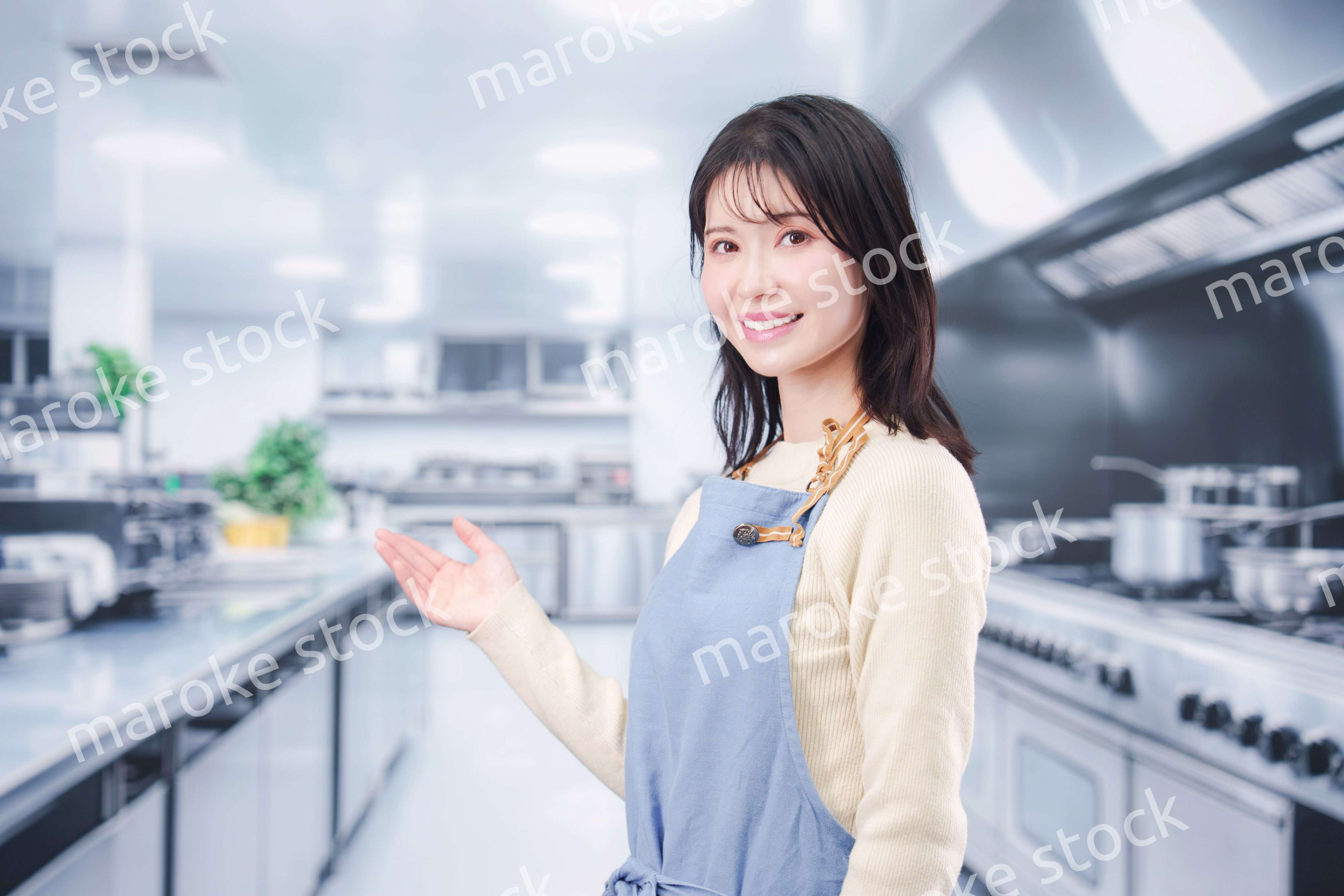 大きな厨房でエプロンを着る若い女性シェフ