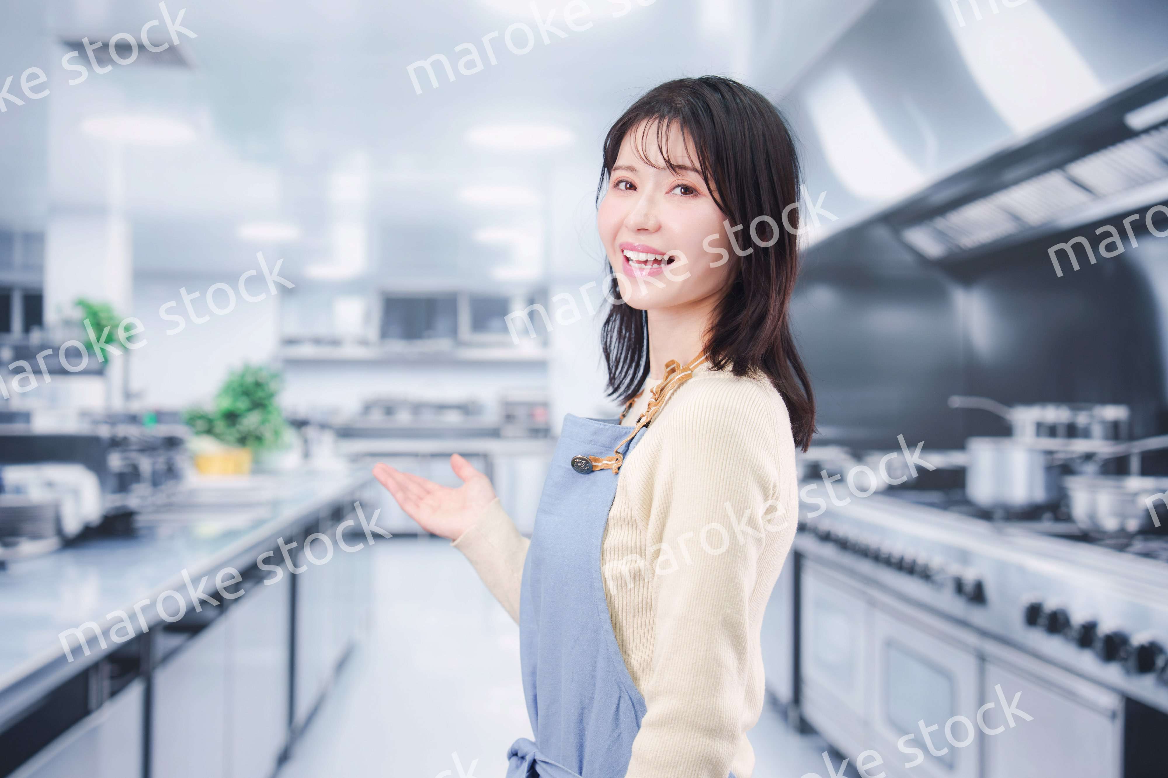 大きな厨房でエプロンを着る若い女性シェフ