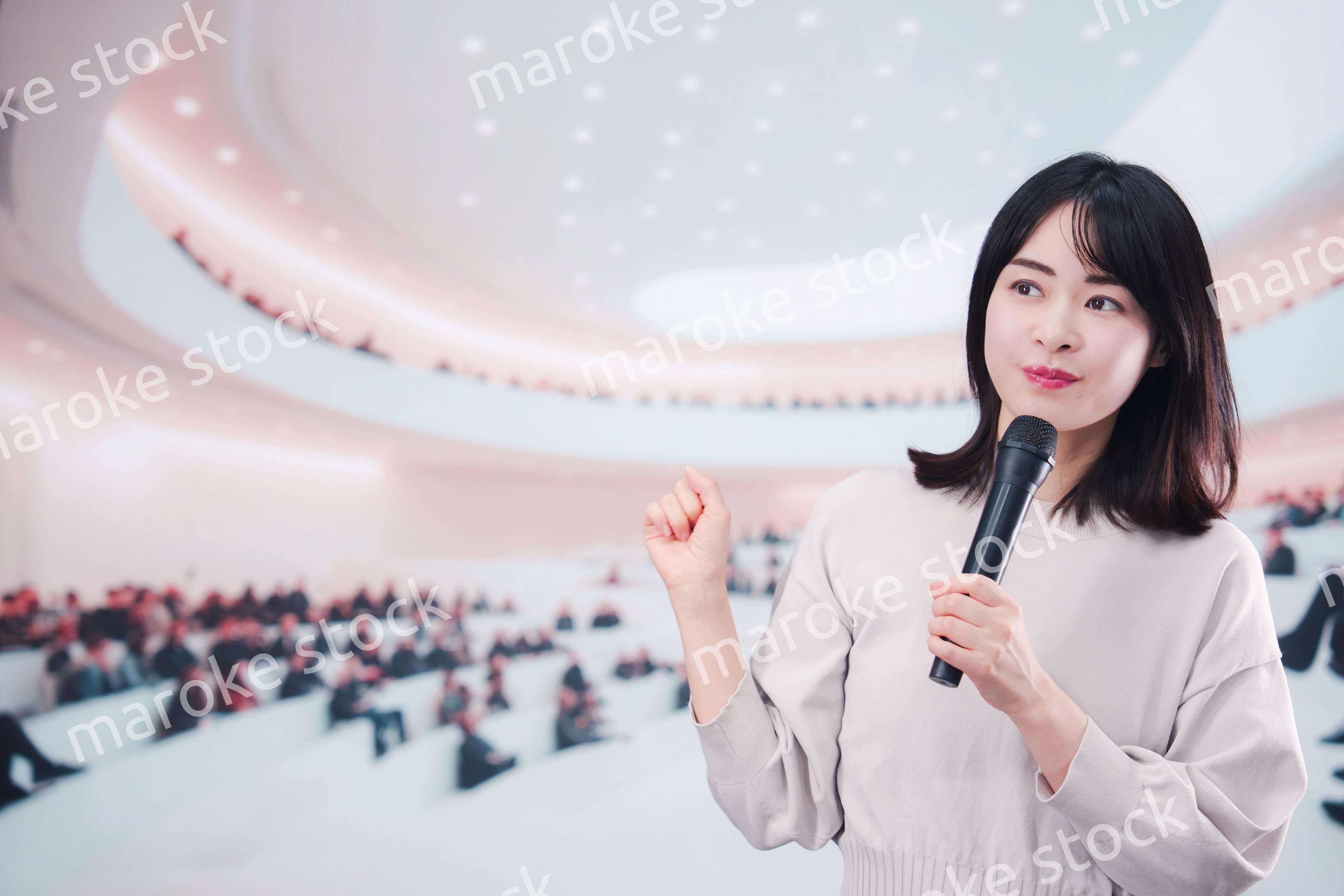 大勢の聴衆の前でマイクで話す女性