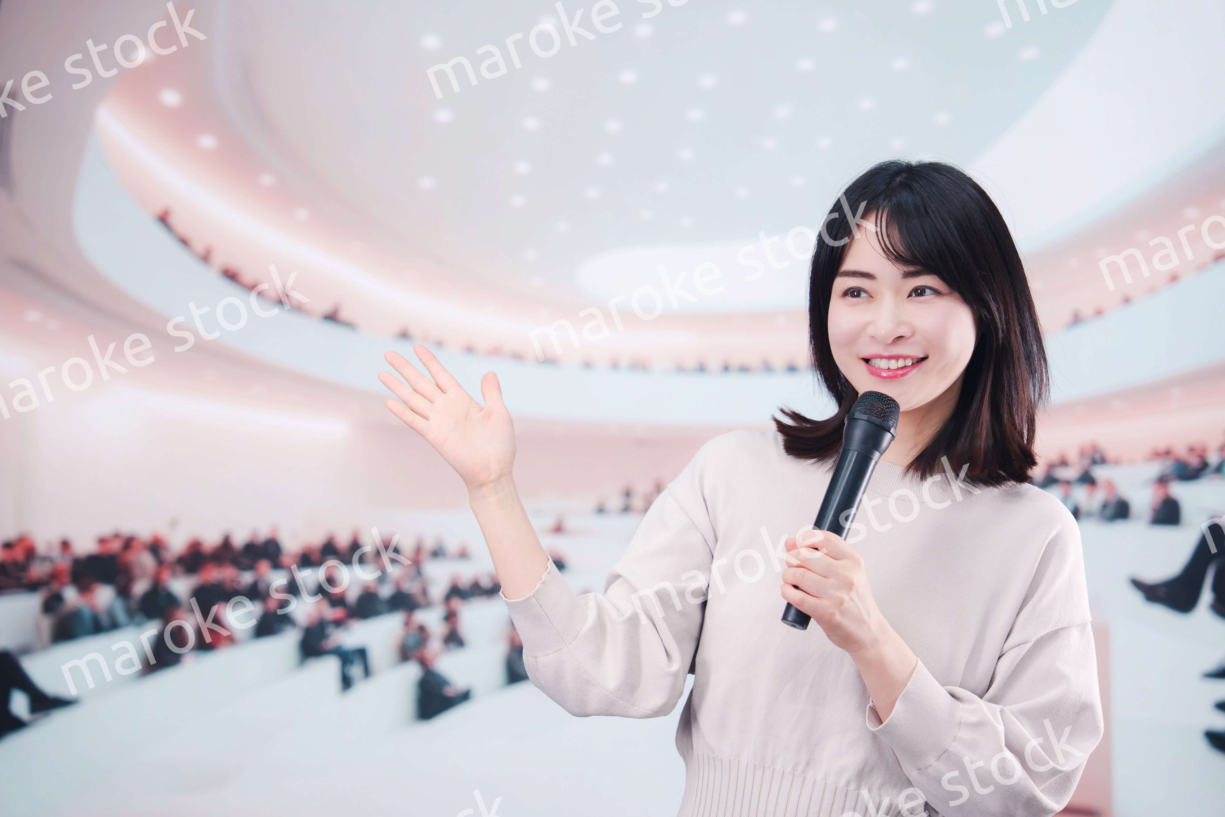 大勢の聴衆の前でマイクで話す女性