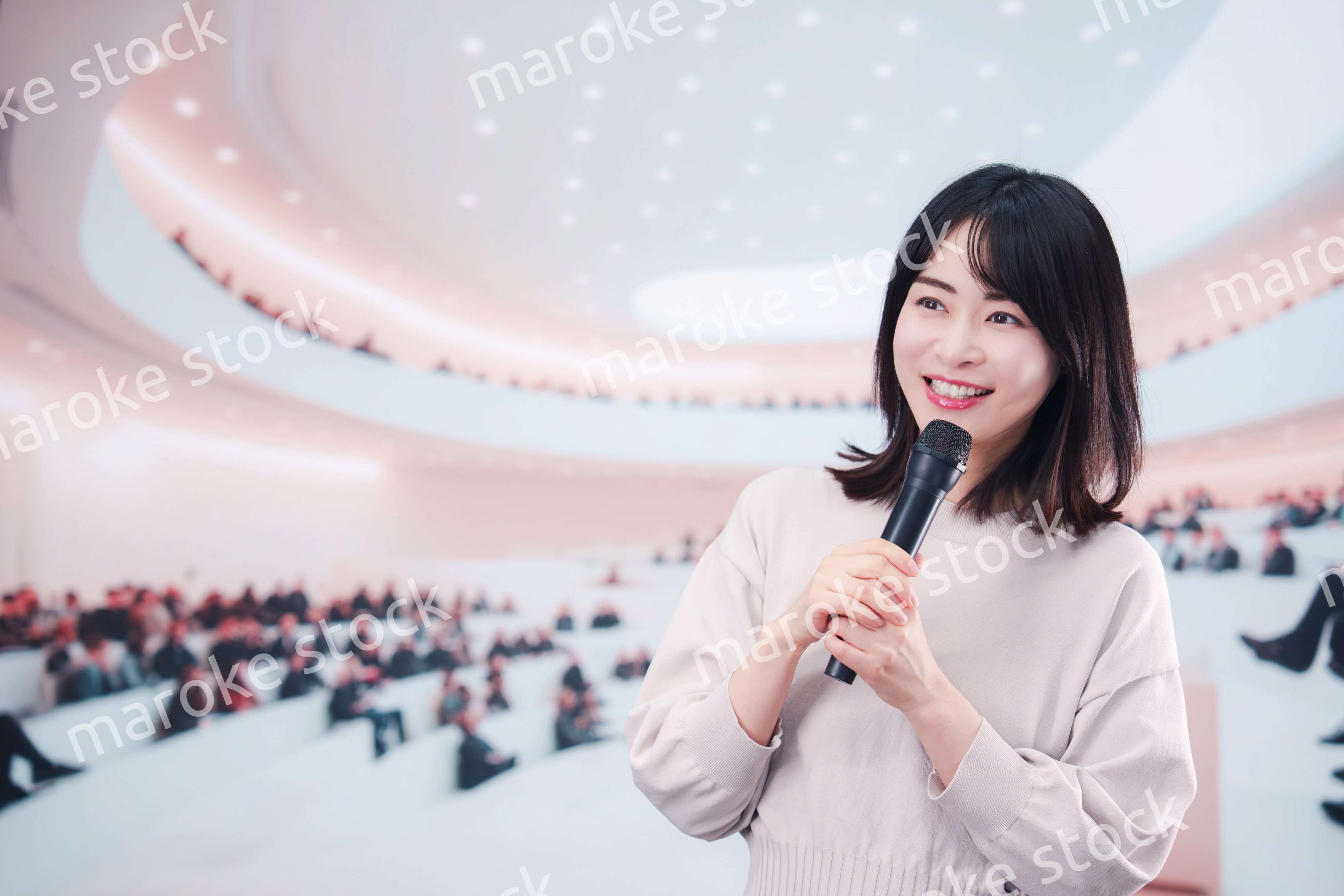 大勢の聴衆の前でマイクで話す女性