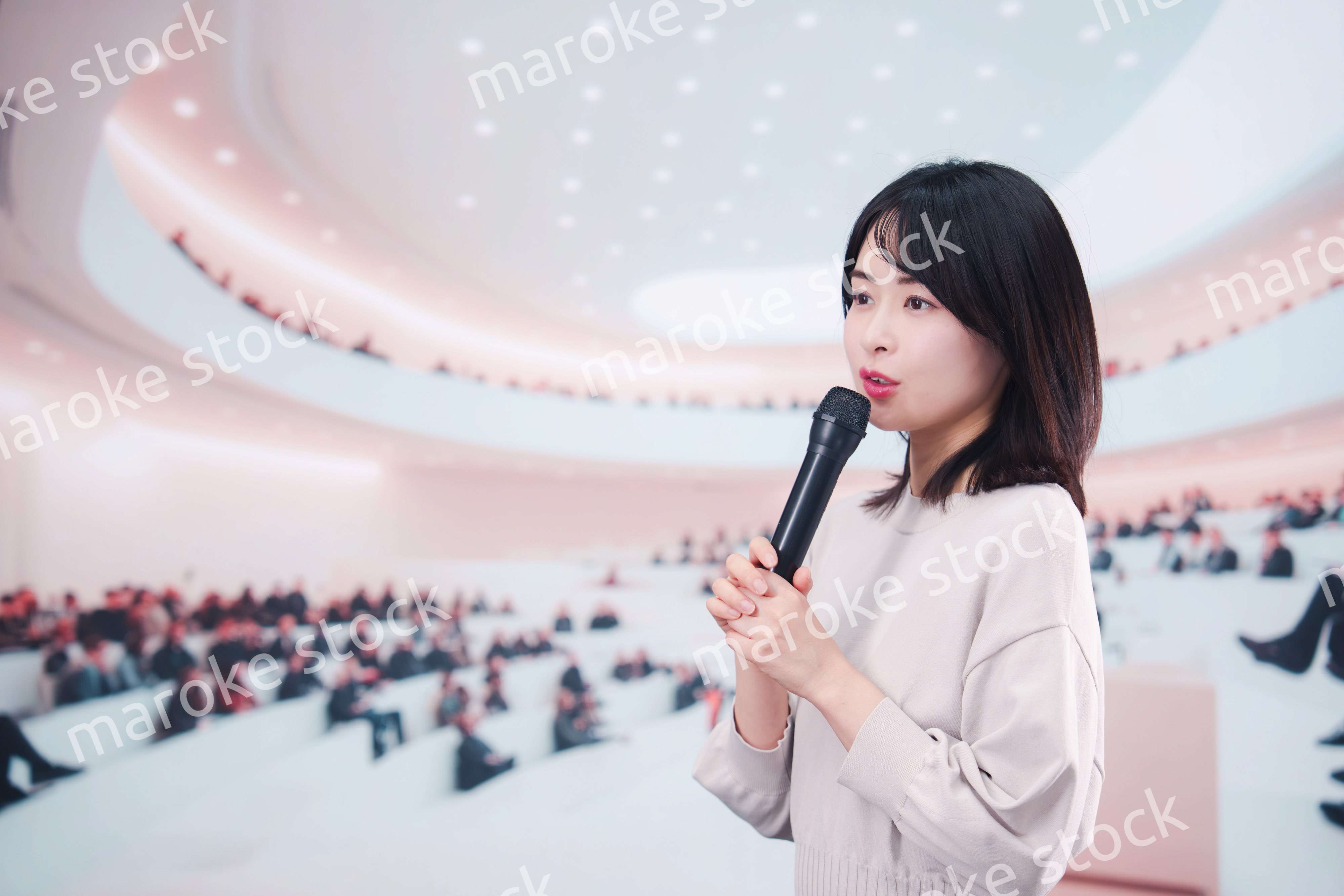 大勢の聴衆の前でマイクで話す女性