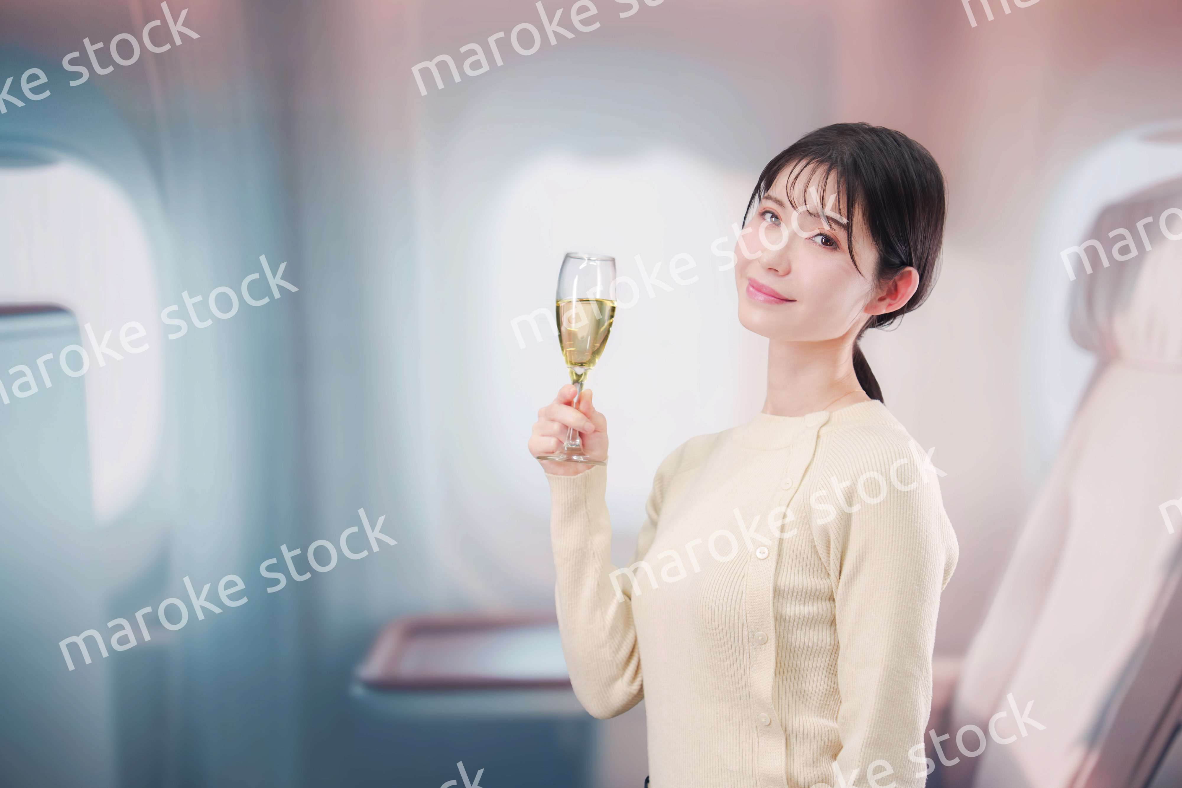 飛行機のビジネスクラスでワインを飲む女性