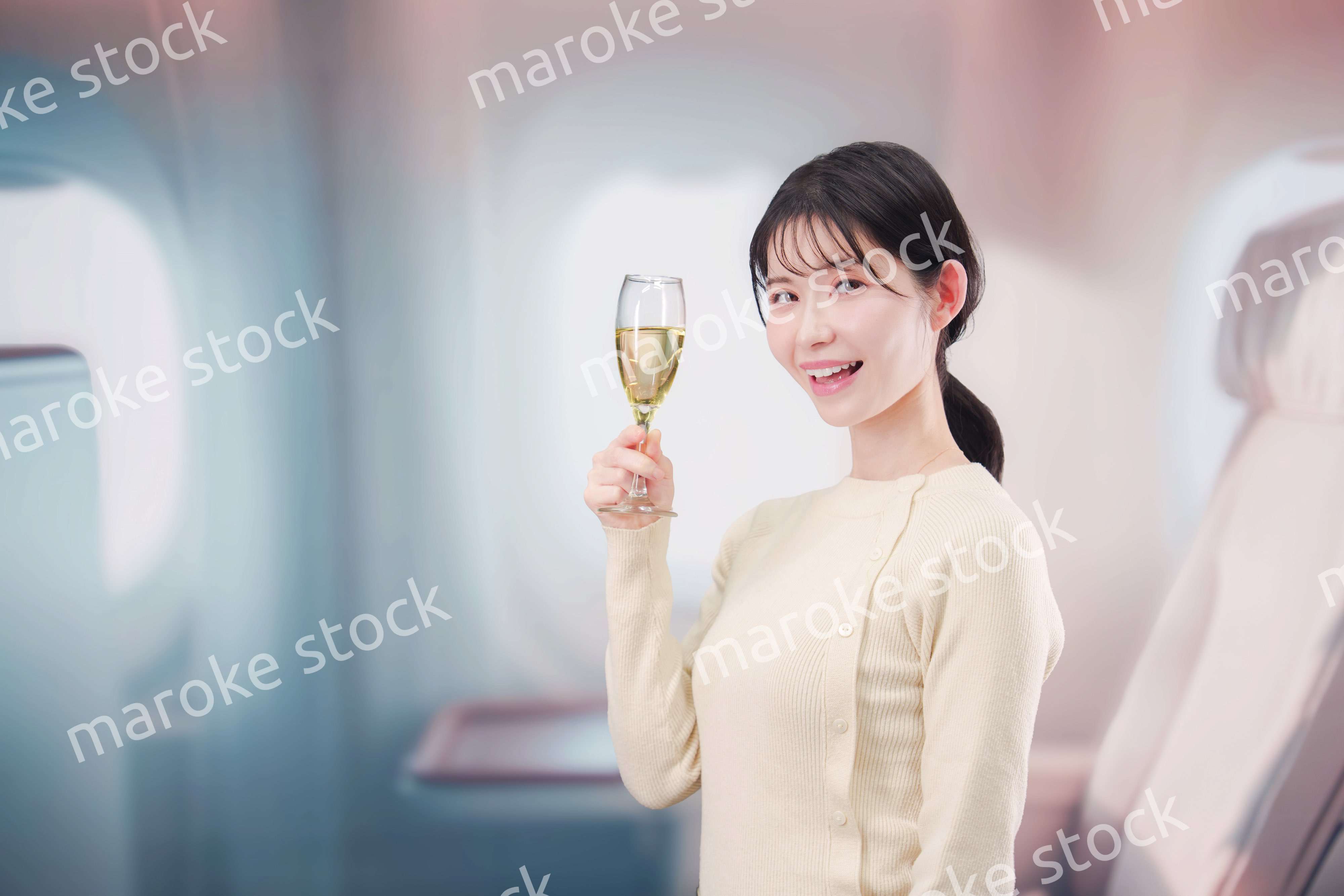 飛行機のビジネスクラスでワインを飲む女性