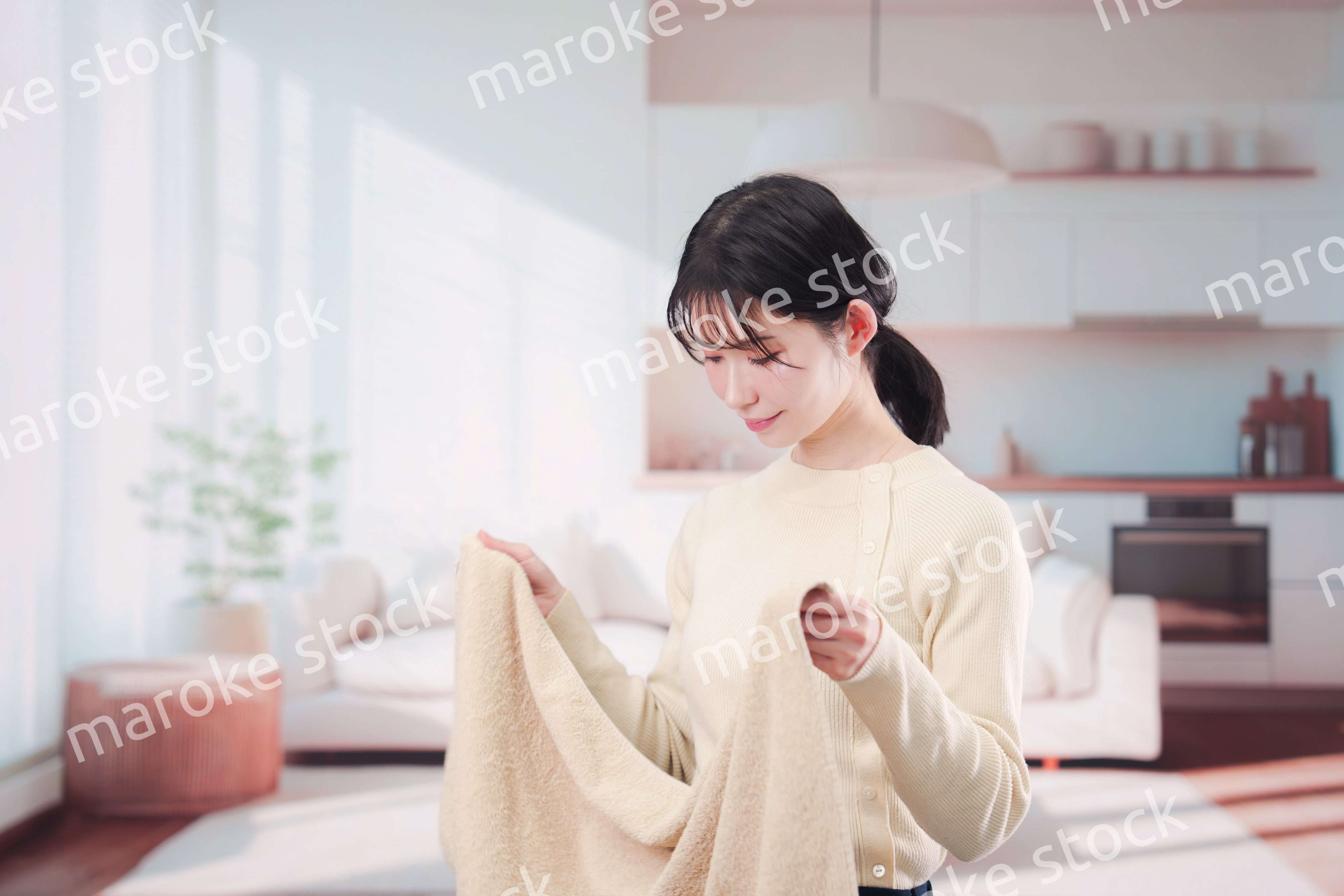 家で洗濯物をたたむ若い女性