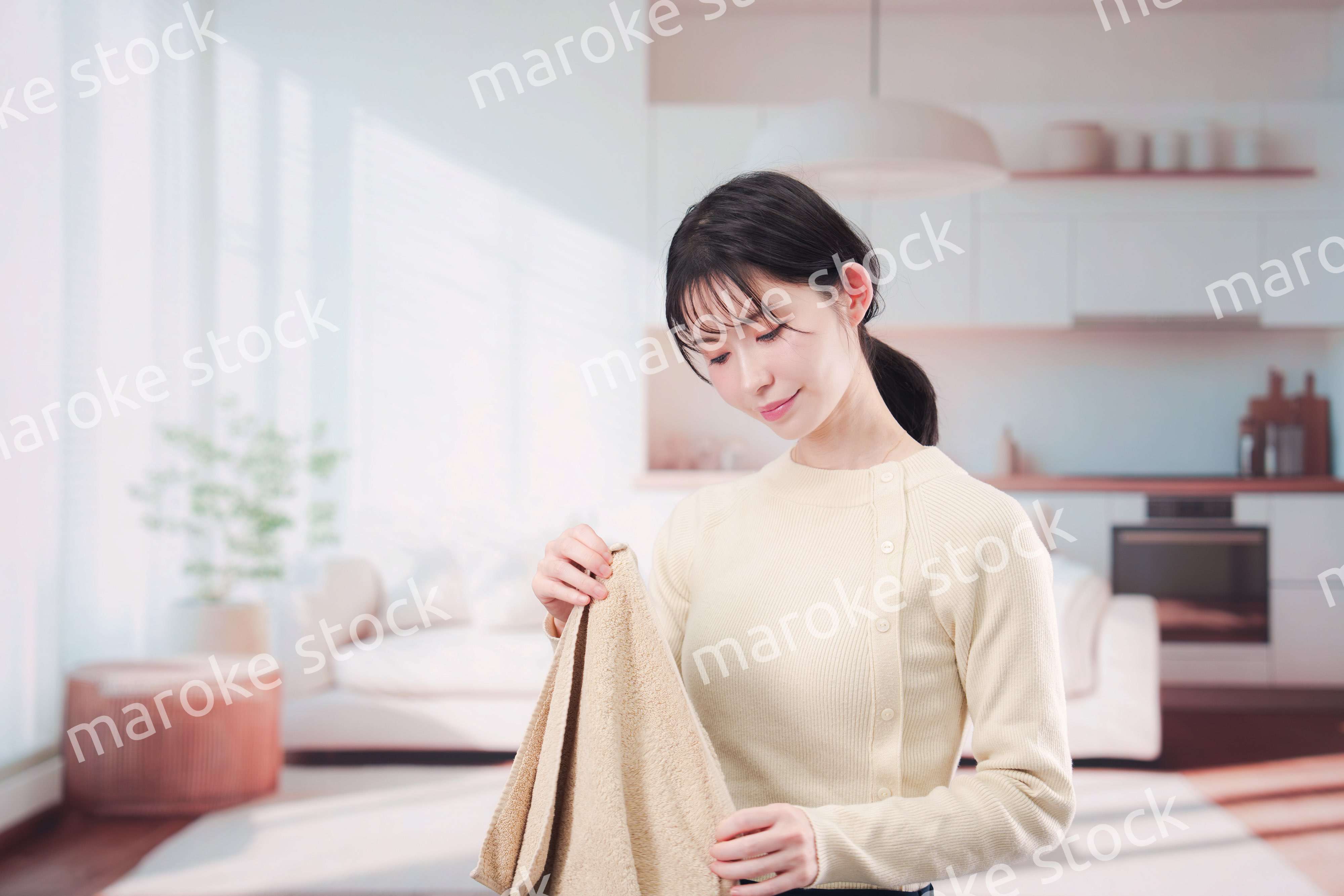 家で洗濯物をたたむ若い女性