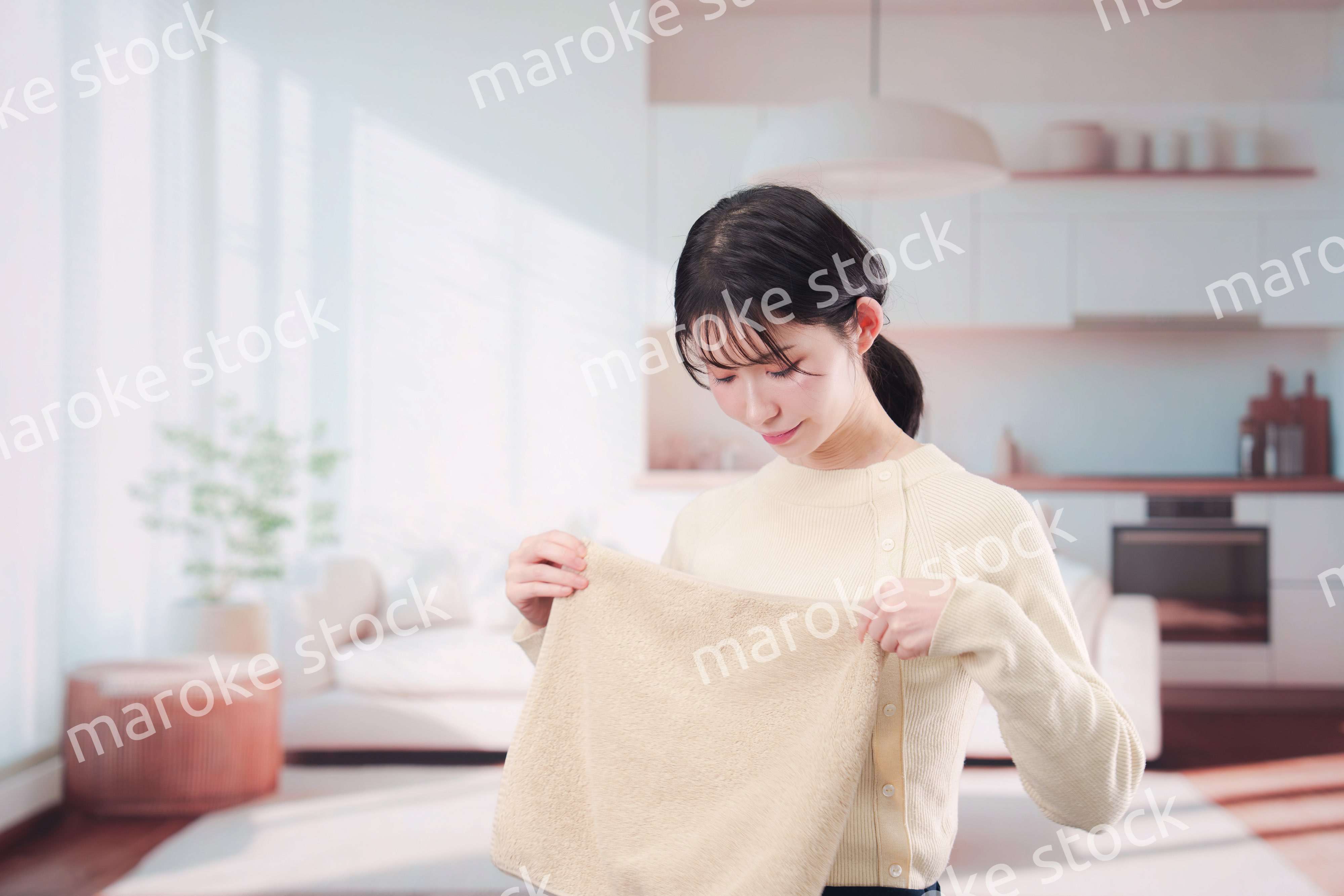 家で洗濯物をたたむ若い女性