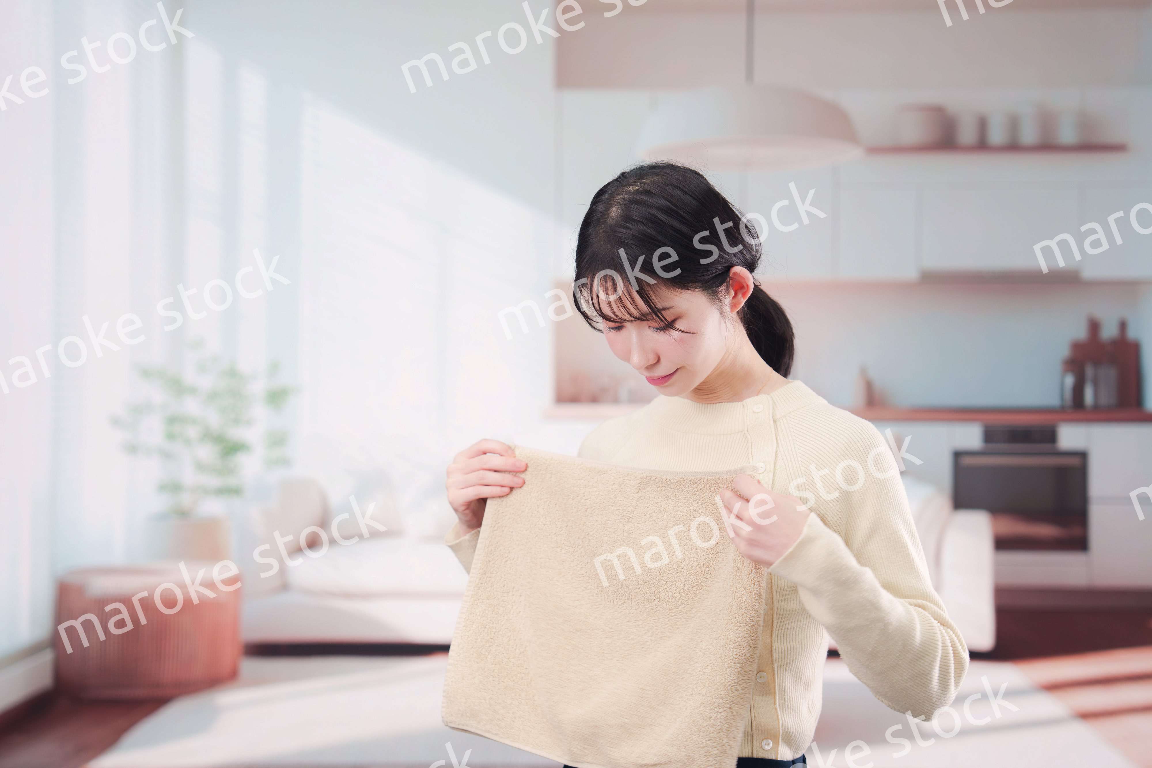 家で洗濯物をたたむ若い女性