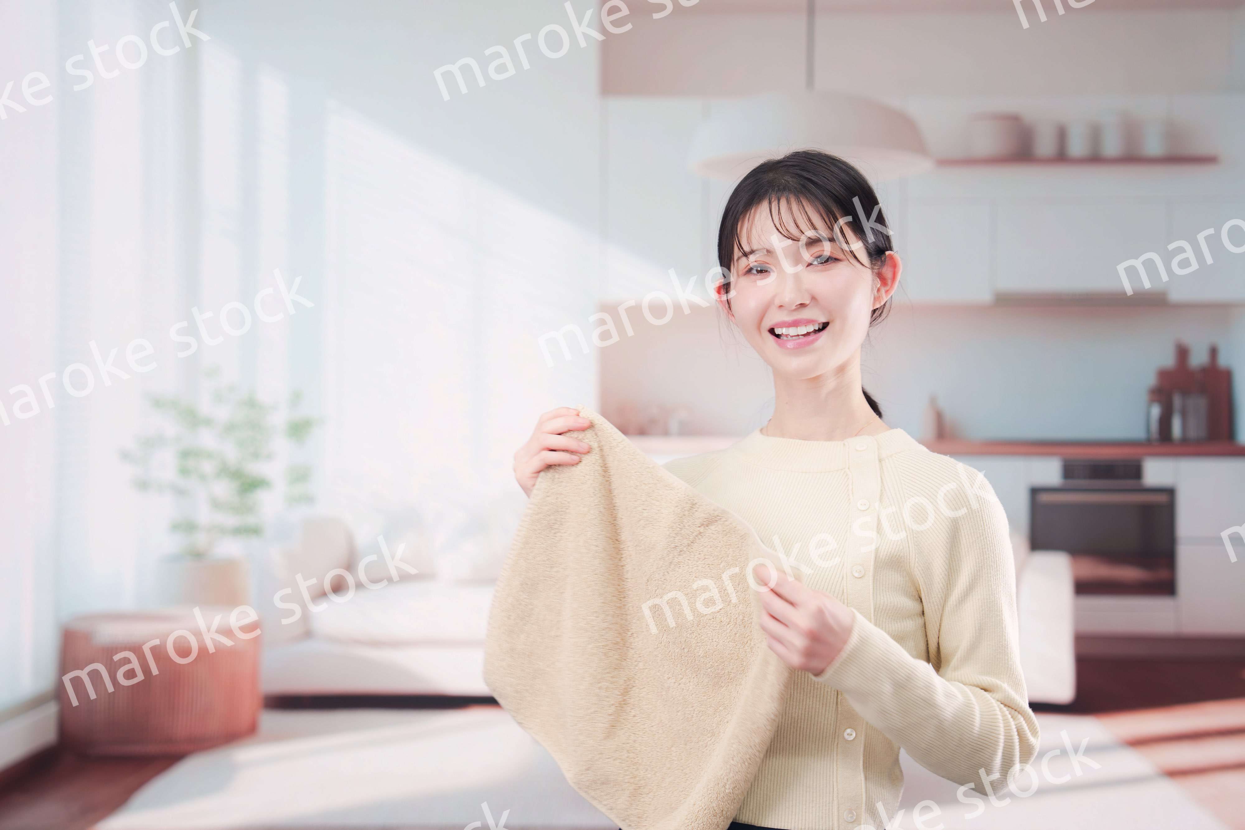 家で洗濯物をたたむ若い女性