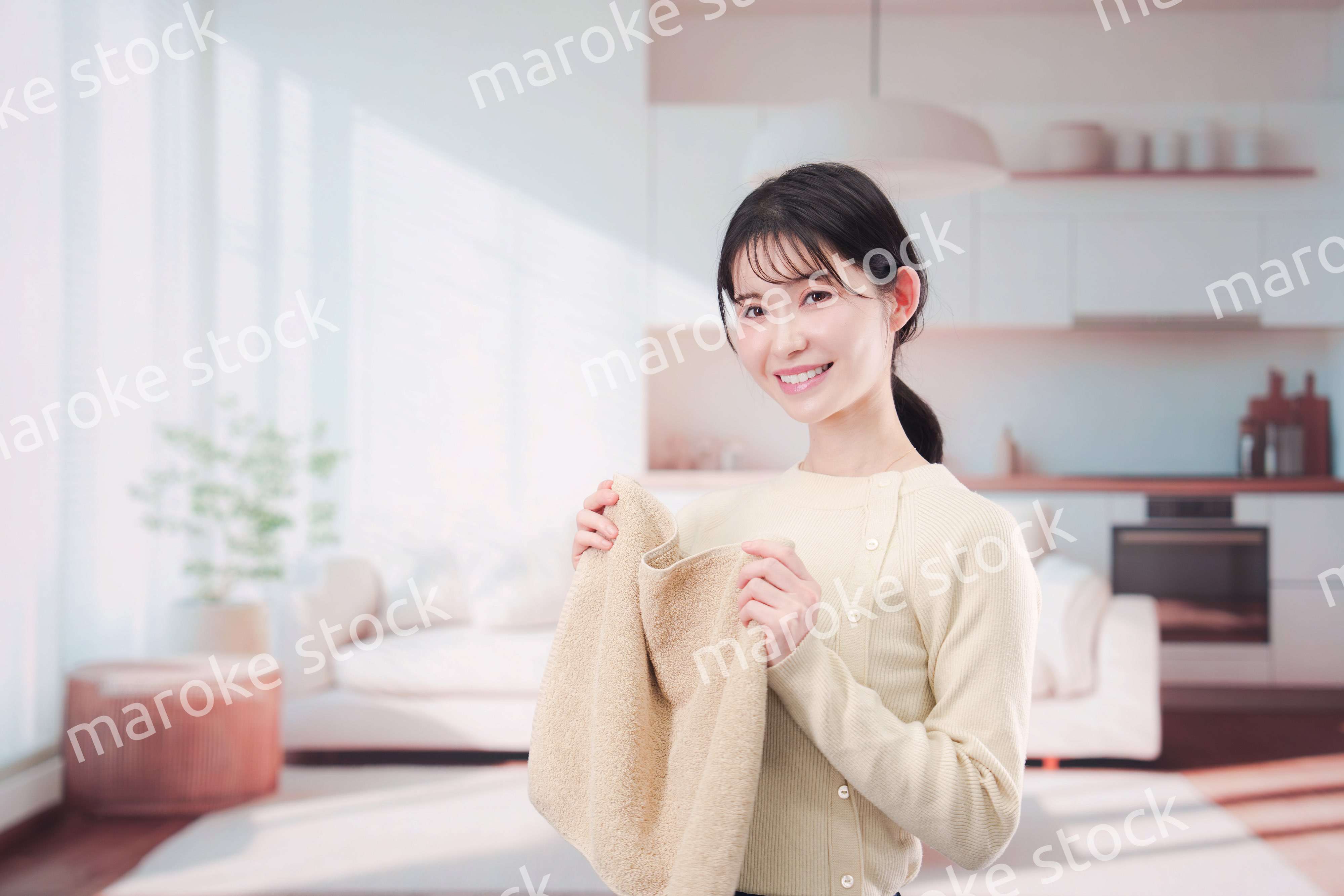 家で洗濯物をたたむ若い女性