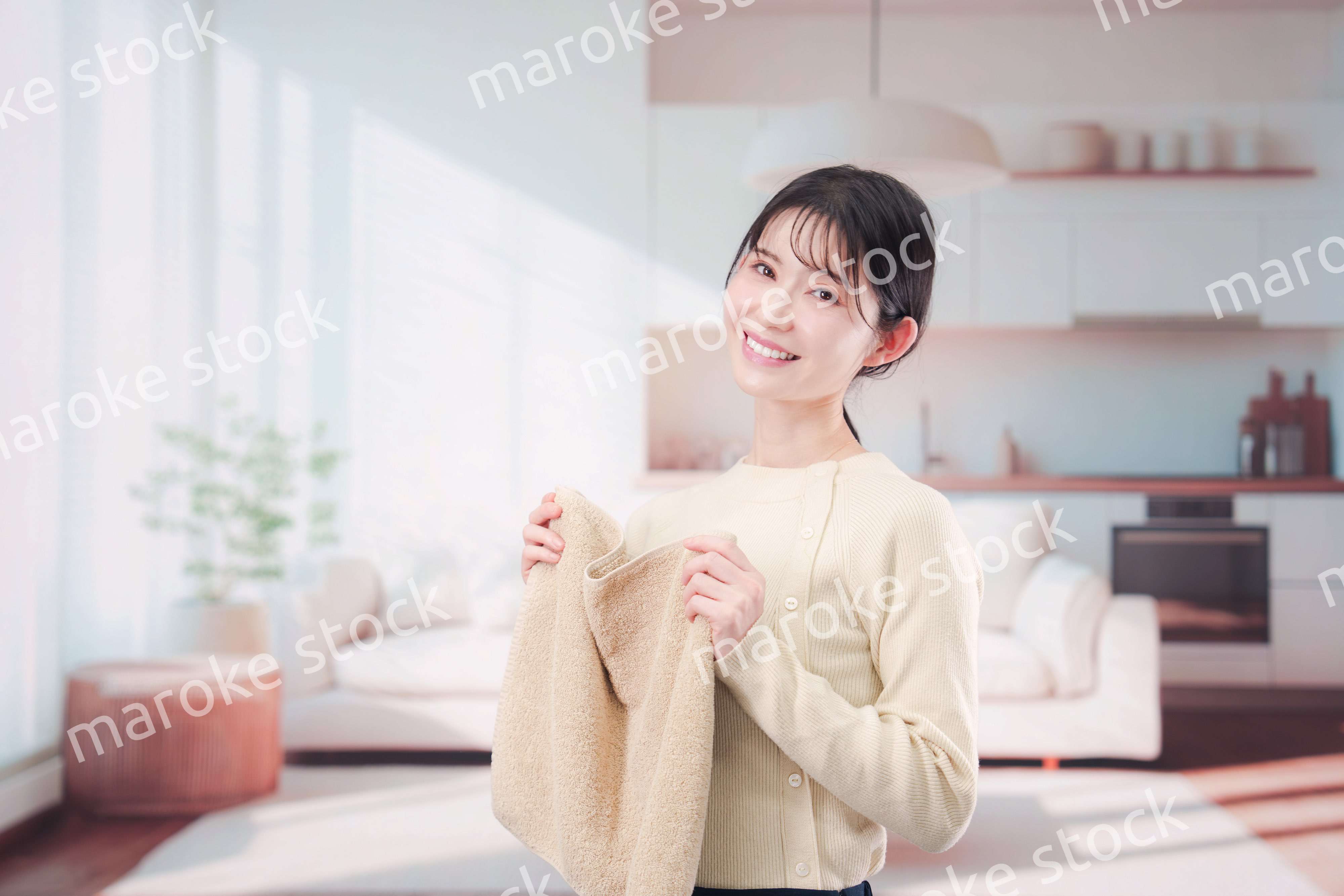 家で洗濯物をたたむ若い女性