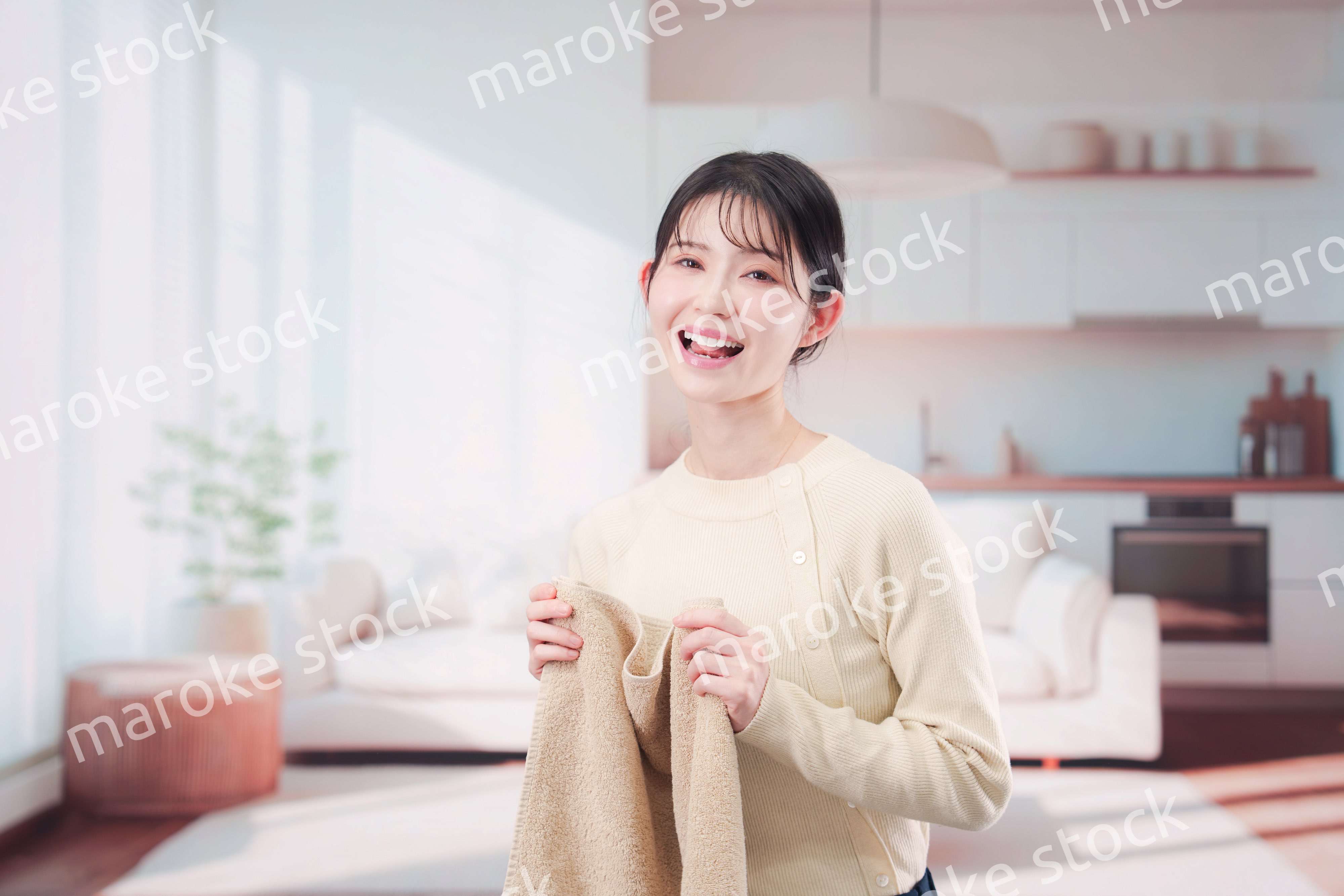 家で洗濯物をたたむ若い女性