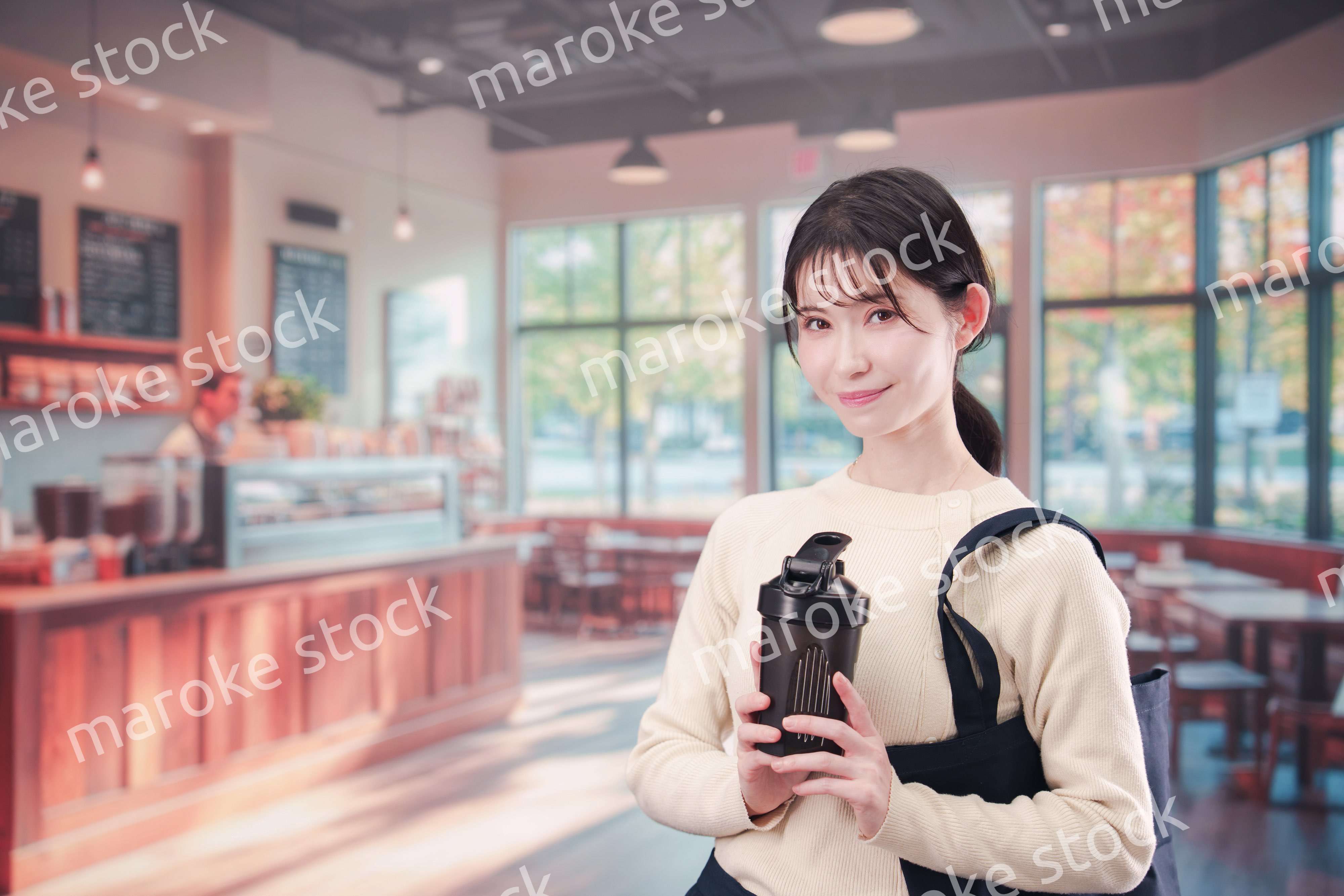 マイカップを持ってカフェに入る若い女性