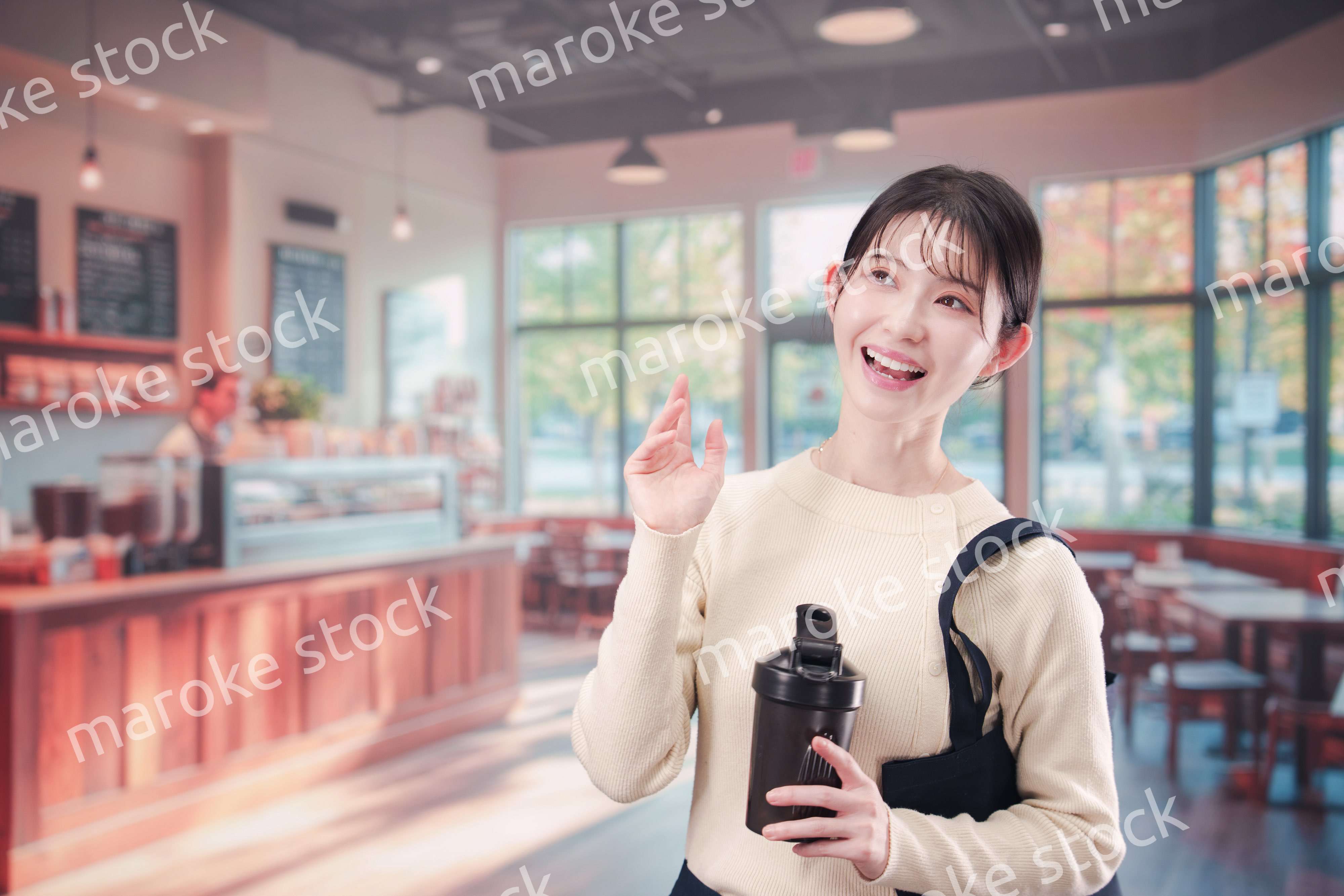 マイカップを持ってカフェに入る若い女性