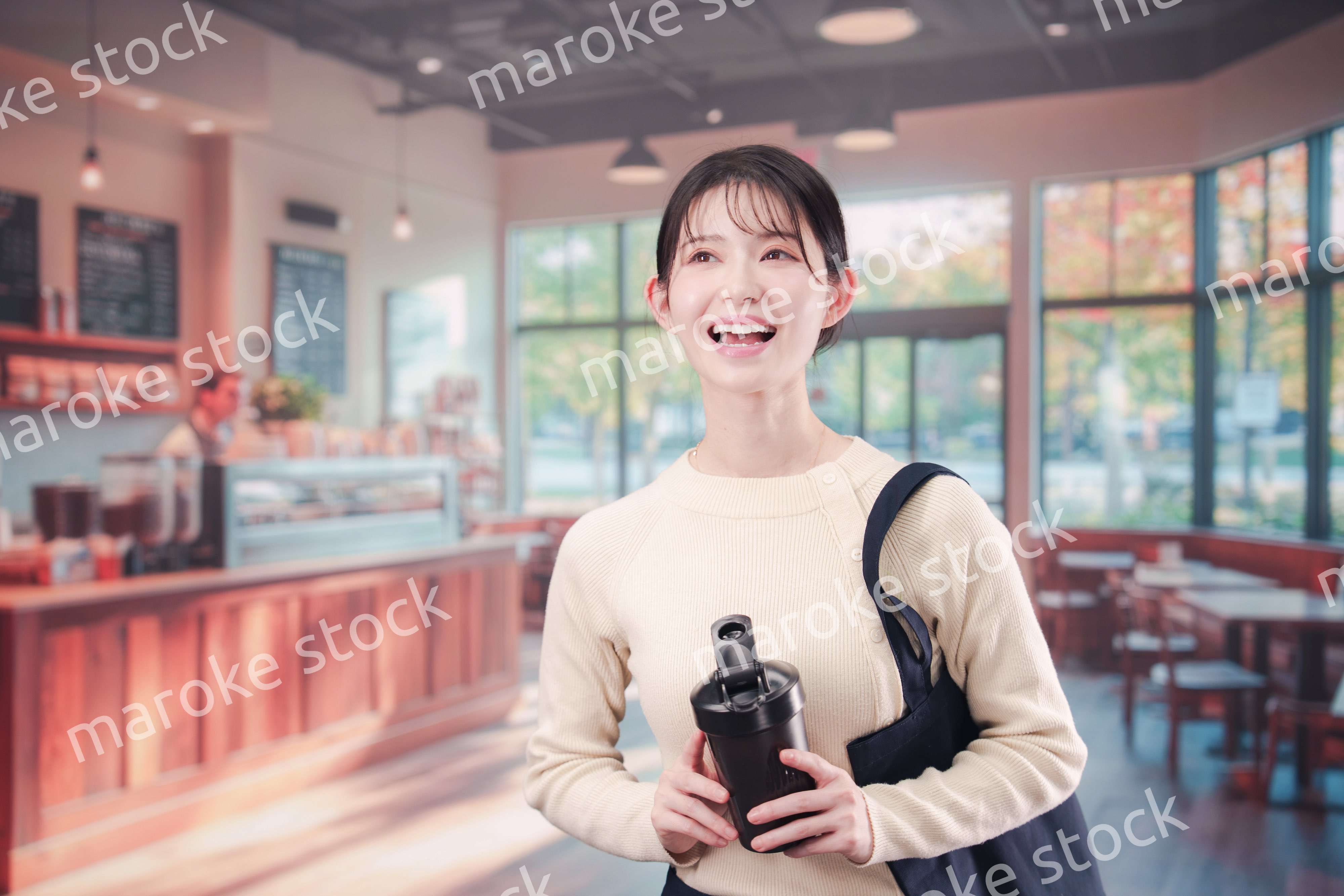 マイカップを持ってカフェに入る若い女性