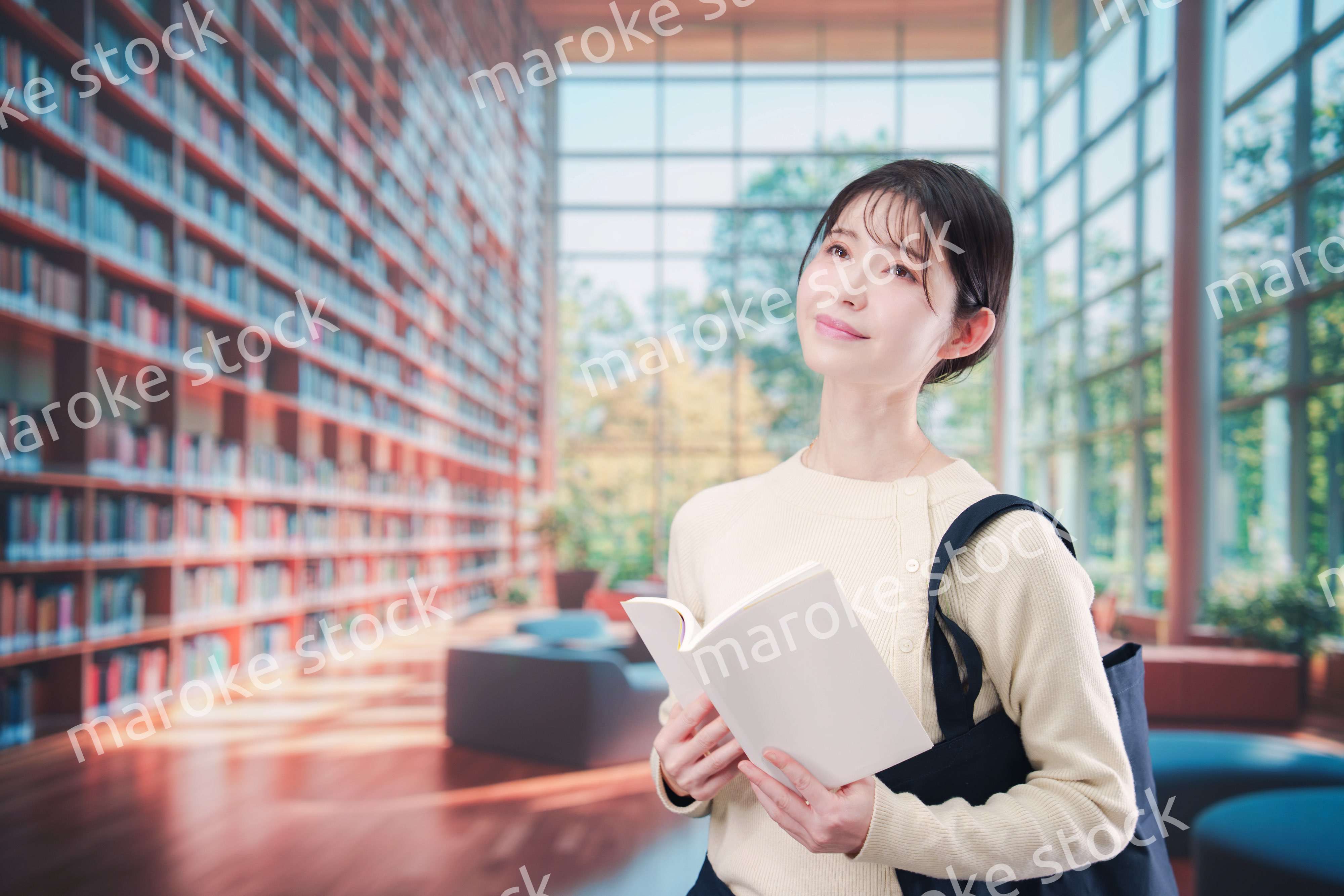 明るい図書館で本を読む若い女性