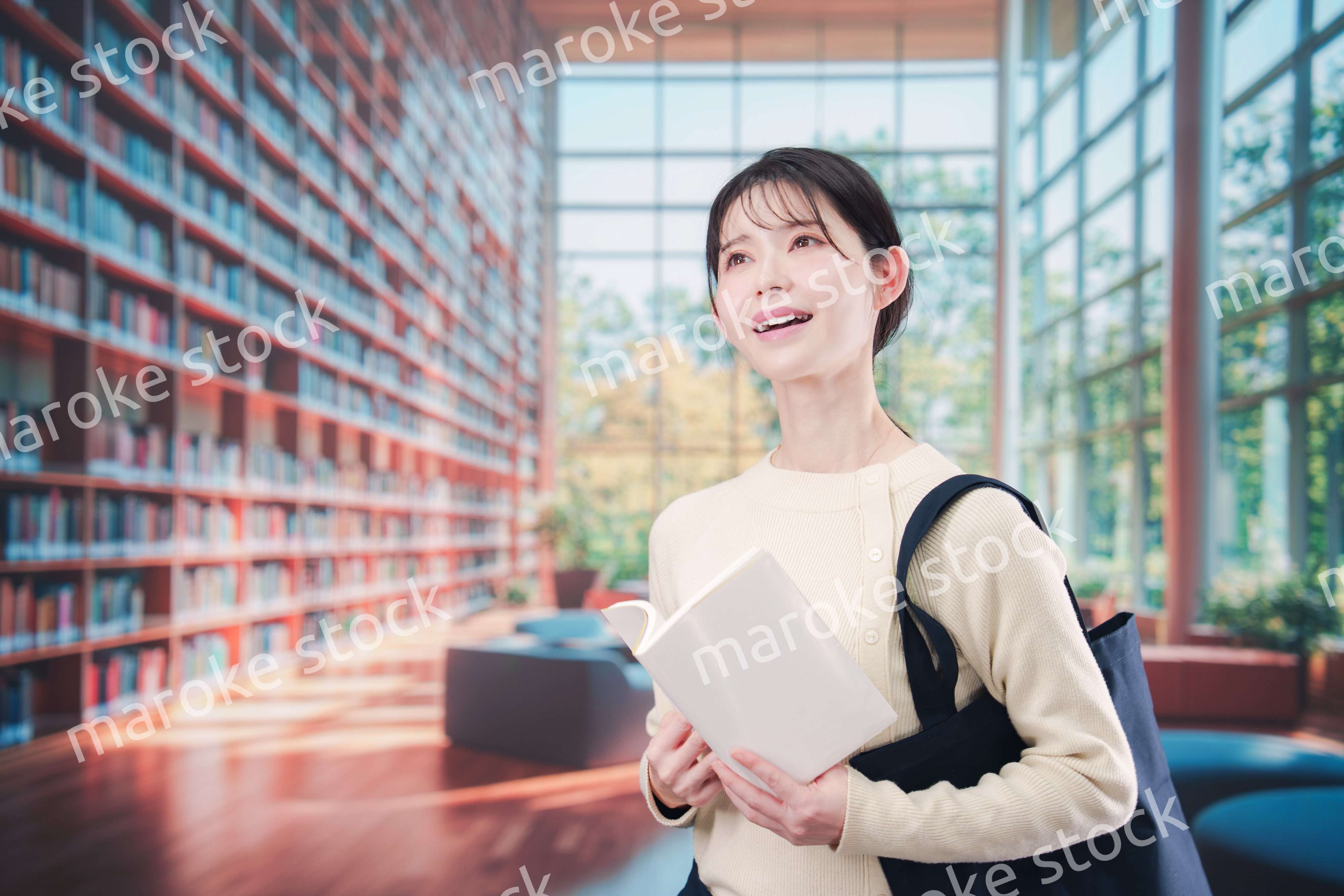 明るい図書館で本を読む若い女性