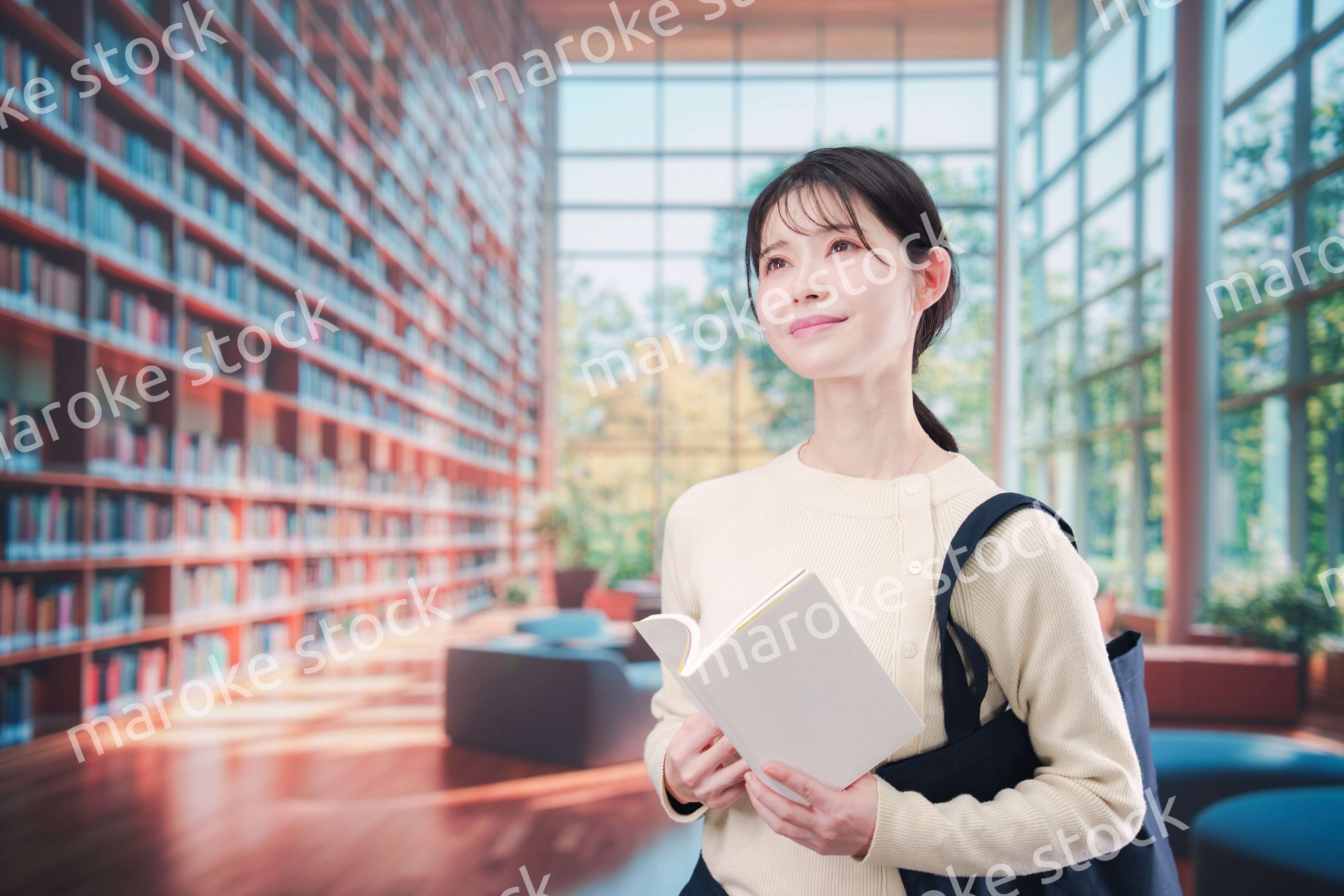 明るい図書館で本を読む若い女性