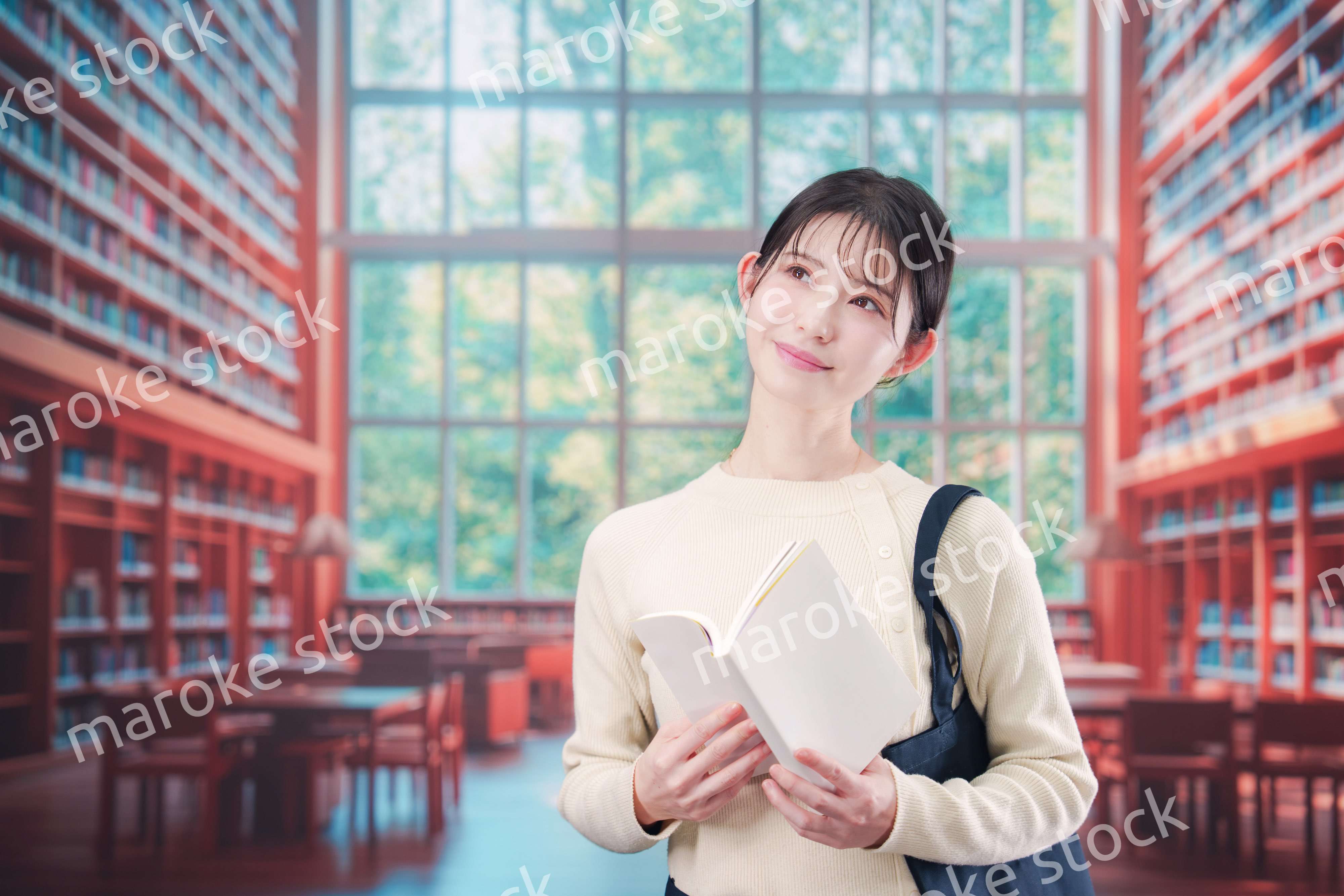 明るい図書館で本を読む若い女性