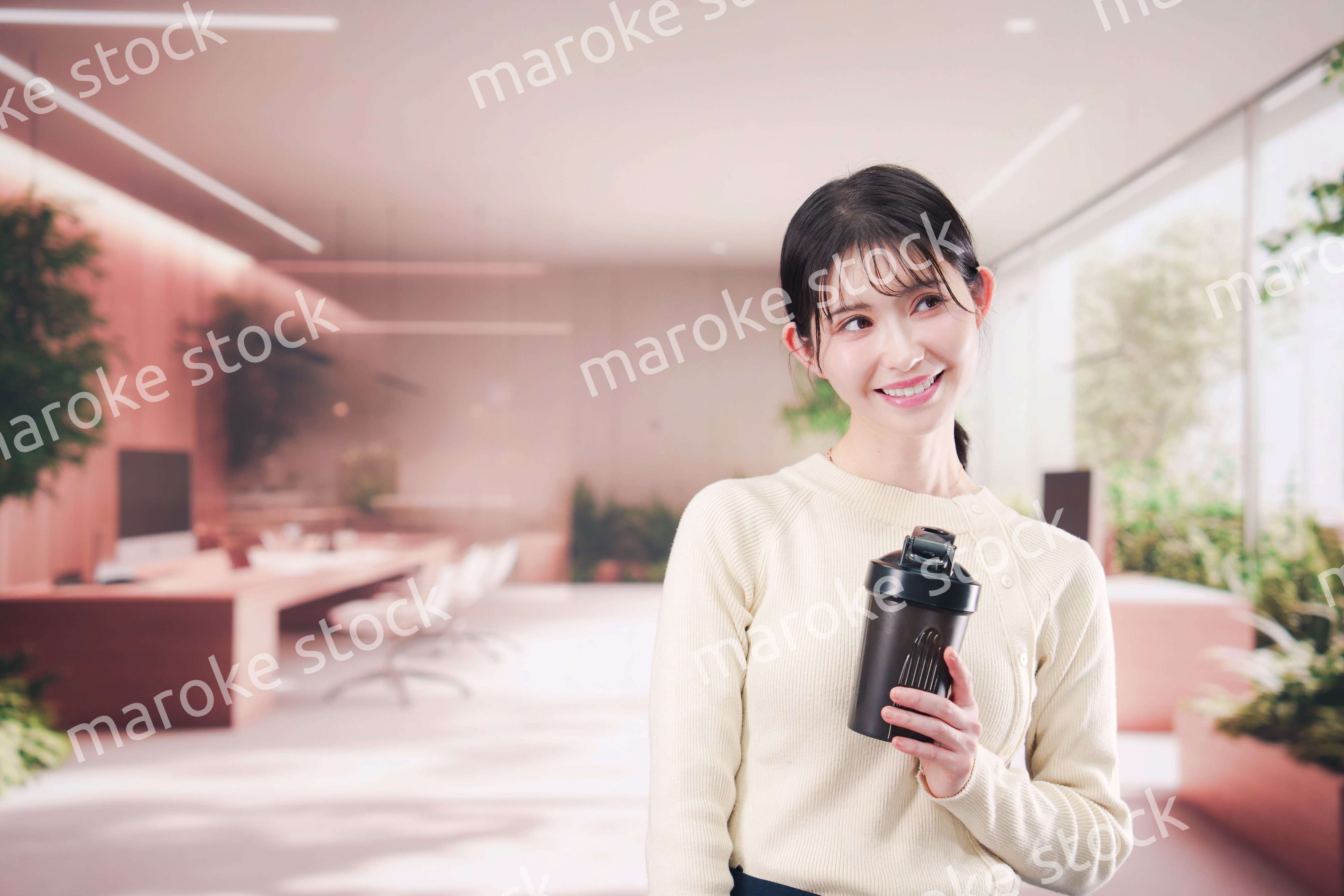 オフィスでマイボトルを持ち歩く若い女性